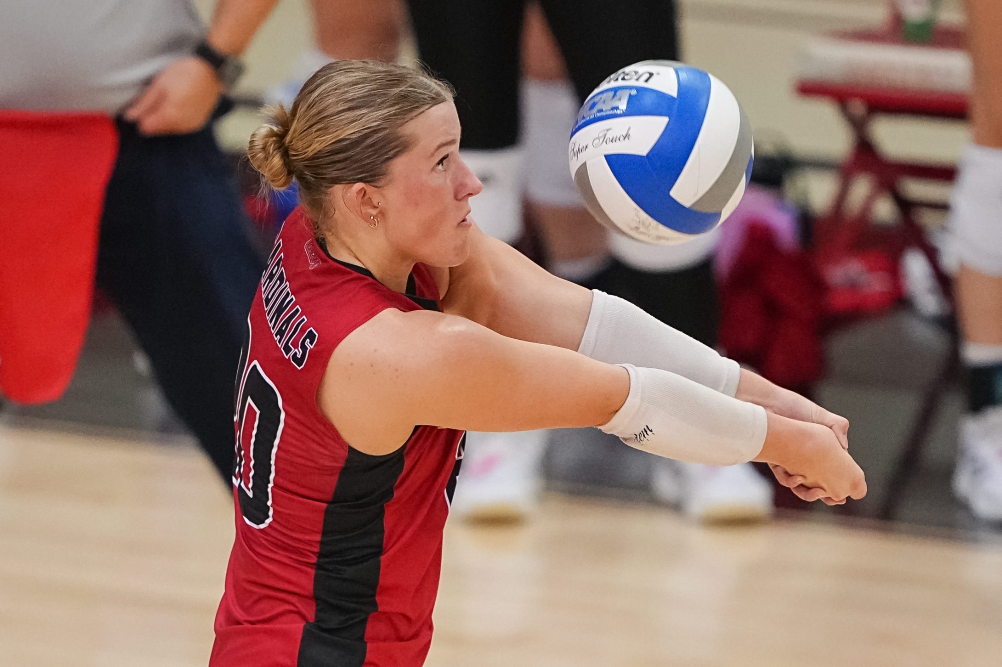 Madison Roney passing a blue and white volleyball while wearing a red jersey with arms extended to the left.