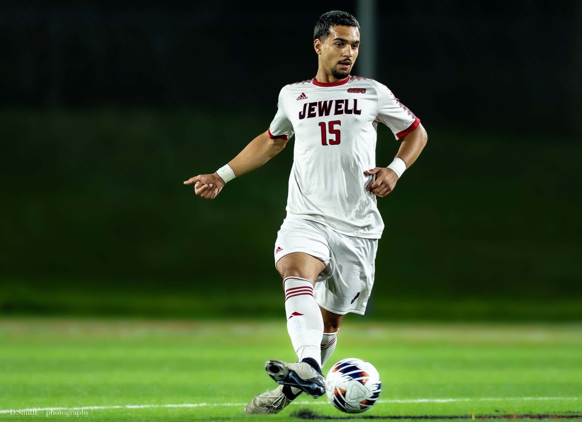 Alan Sari passes a soccer ball with his foot in a white Jewell uniform 