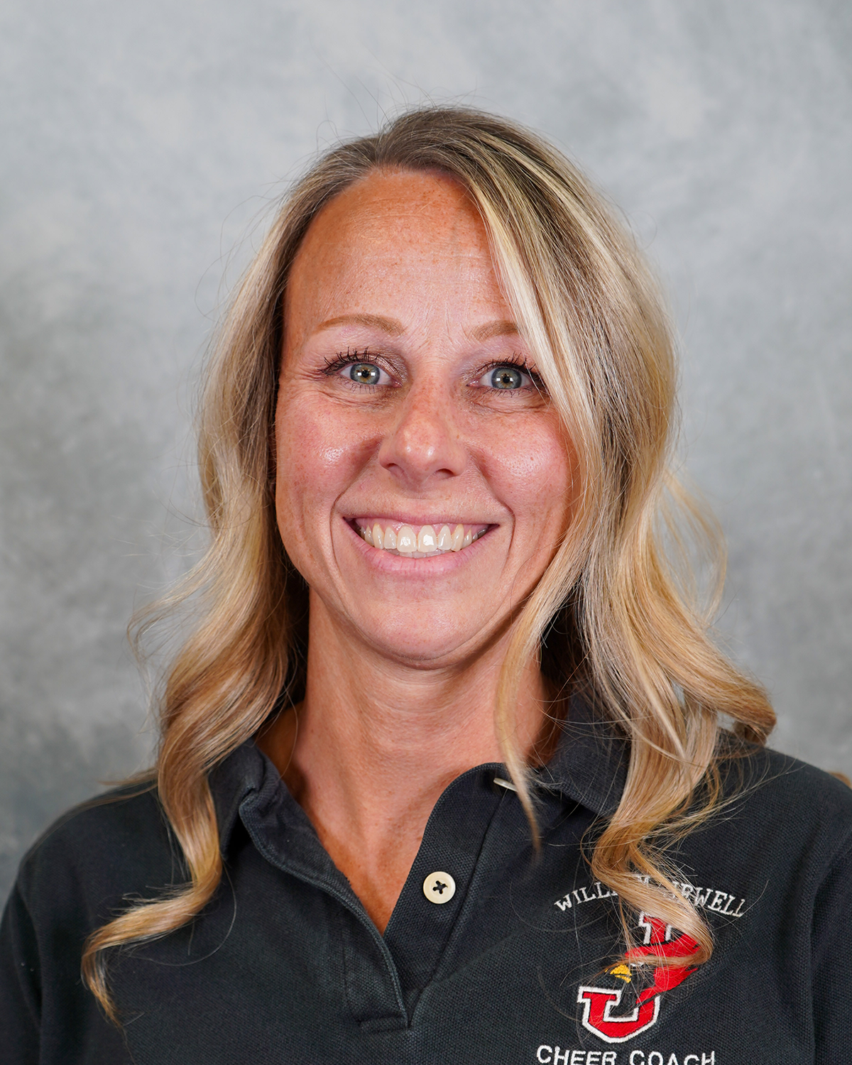 Tricia Mendel poses for a headshot wearing a black polo against a gray background