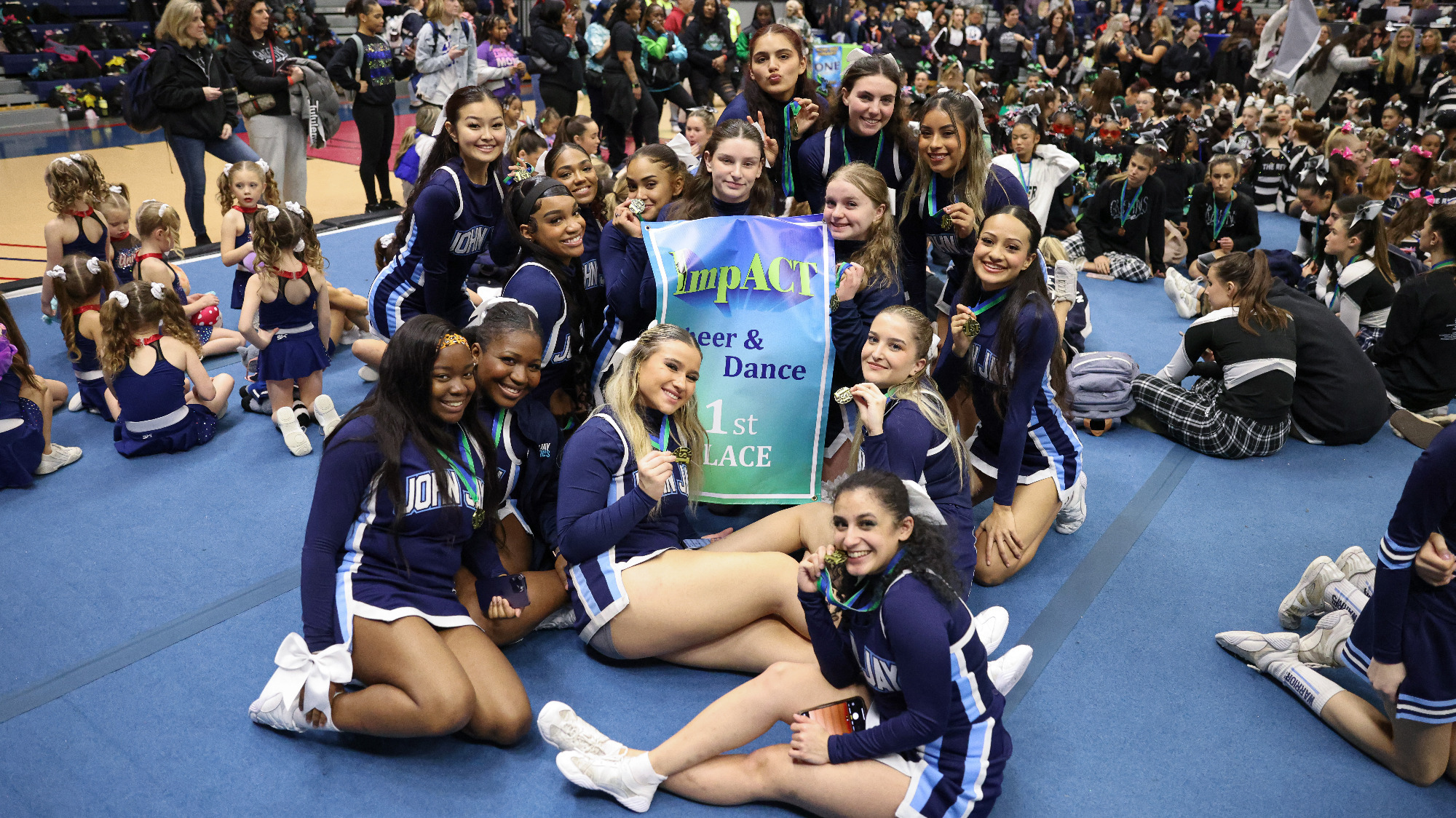 John Jay Cheerleading team poses with their first place banner at the 2024 ImpACT Cheer and Dance Challenge