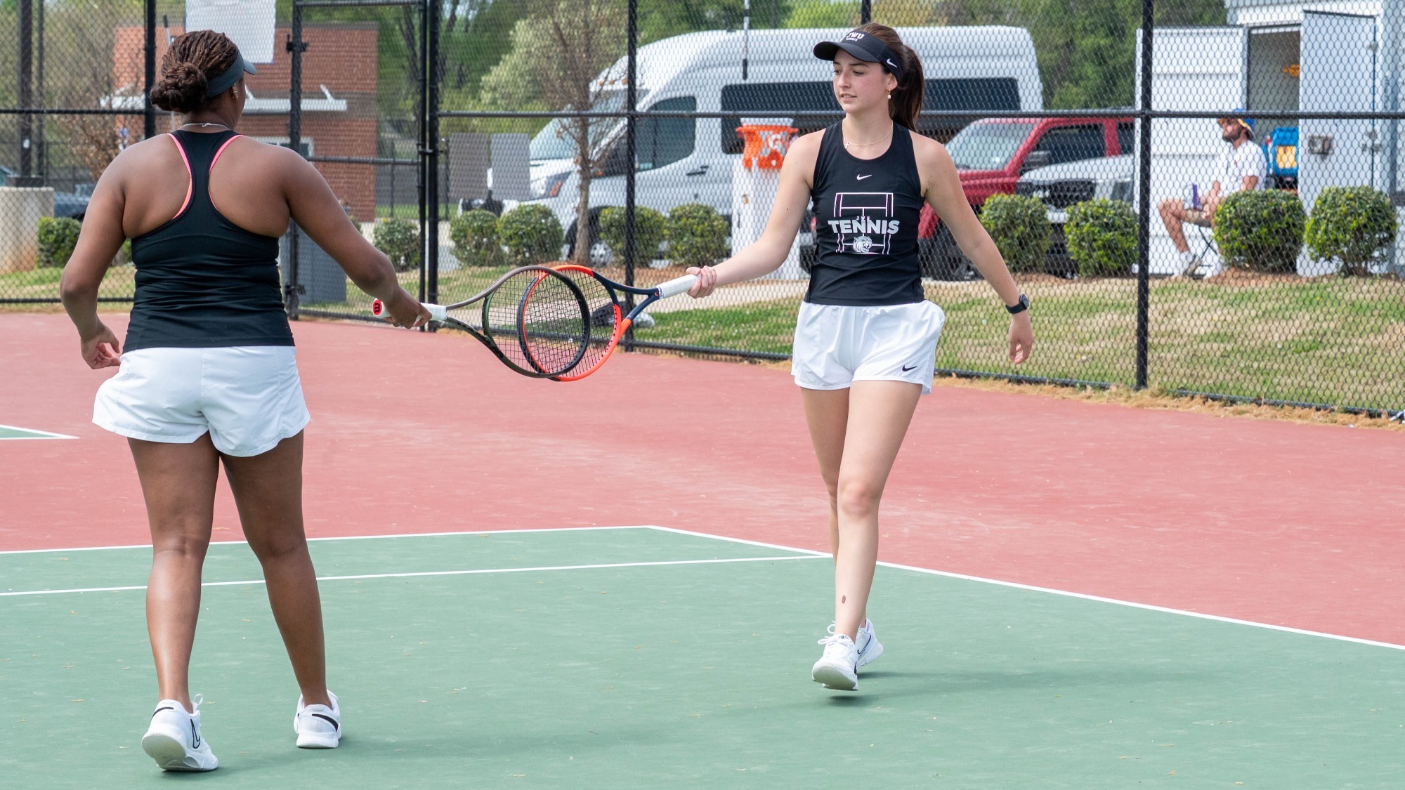 two women touching tennis rackets together