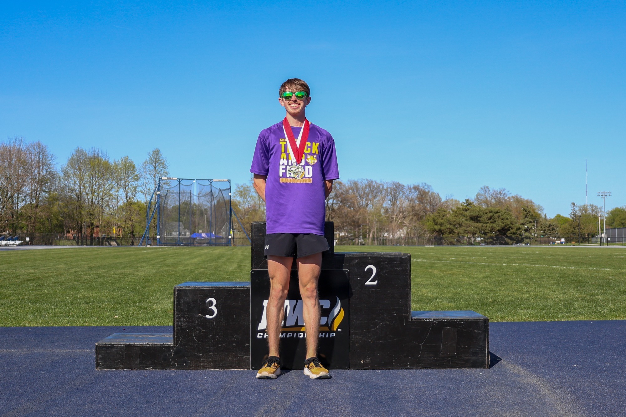 Lance Miller in front of the podium after earning the Elite 20 Award at the 2025 MWC Outdoor Track & Field Championships