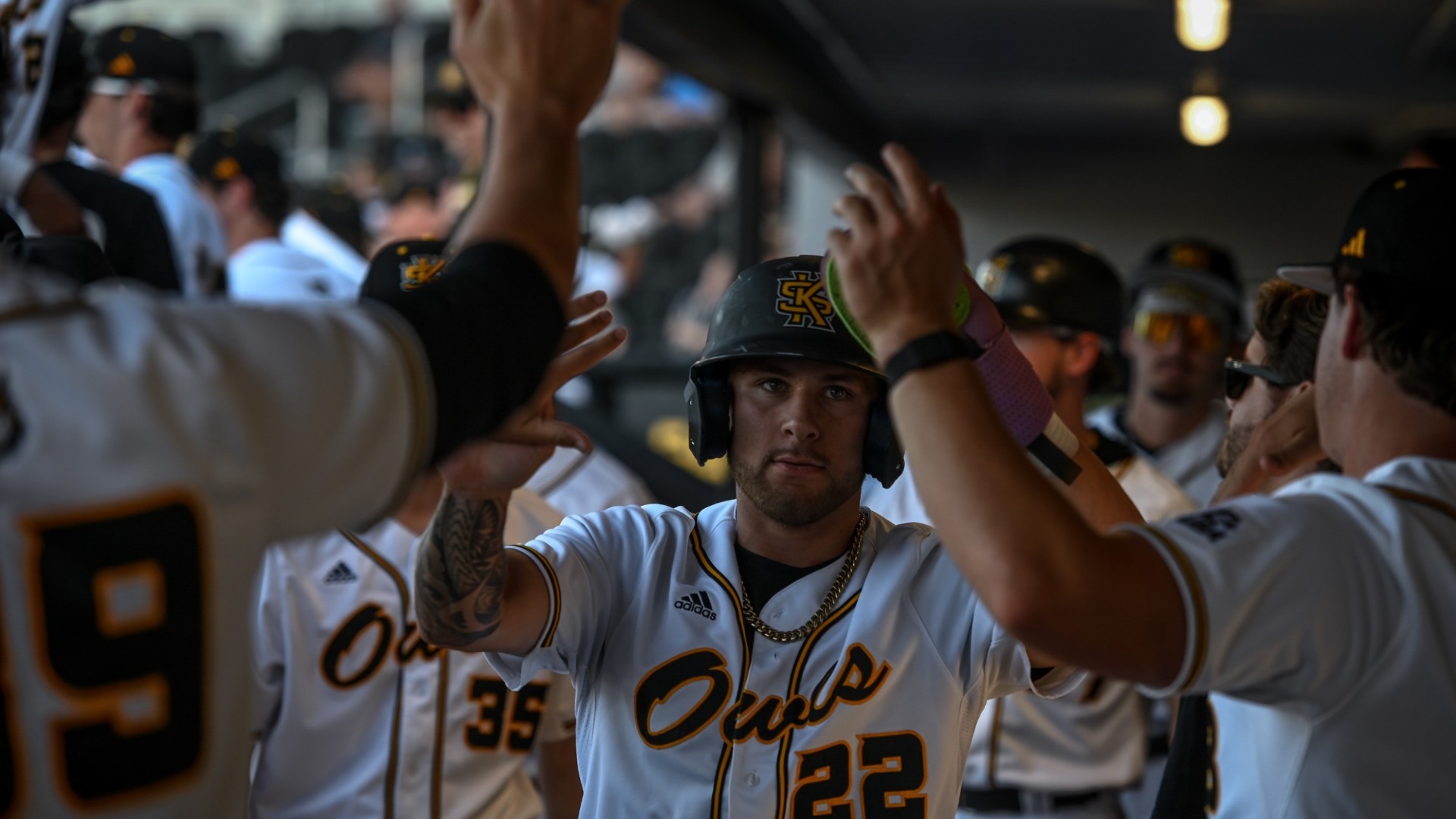 Cooper Williams high-fiving teammates in the dugout after scoring a run against Mercer