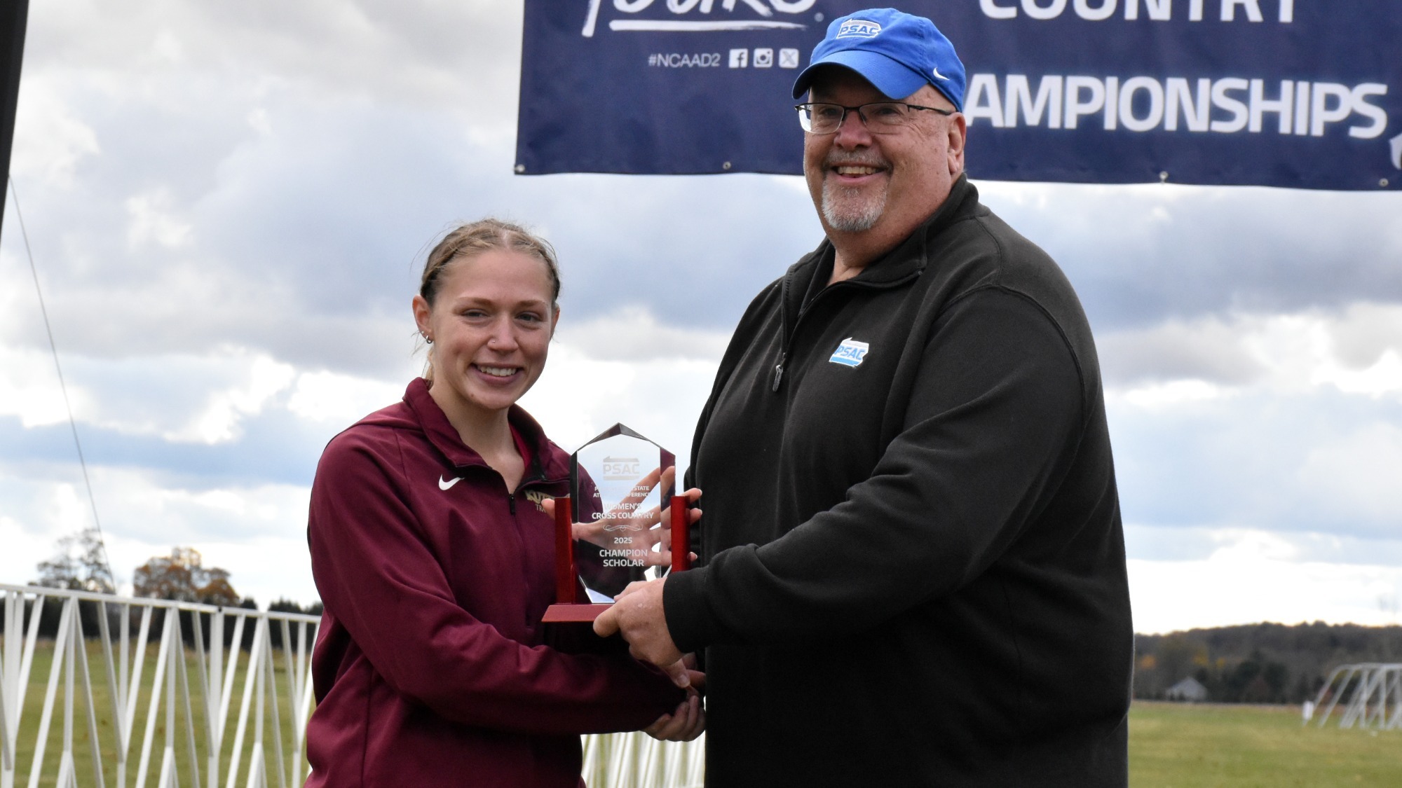 Sophia Knerr of the Kutztown University women's cross country team accepts the 2025 PSAC Women's Cross Country Champion Scholar award from PSAC commissioner Steve Murray at the PSAC Championships in Edinboro, Pa., on Saturday, Oct. 25, 2025.