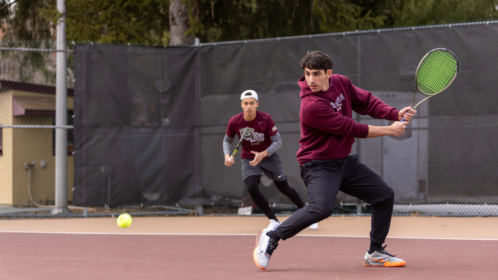 Henrique Rocha of the Kutztown University men's tennis team hits a backhand shot during the No. 1 doubles match with partner Dang Nguyen against Marymount (Va.) on March 26, 2025.