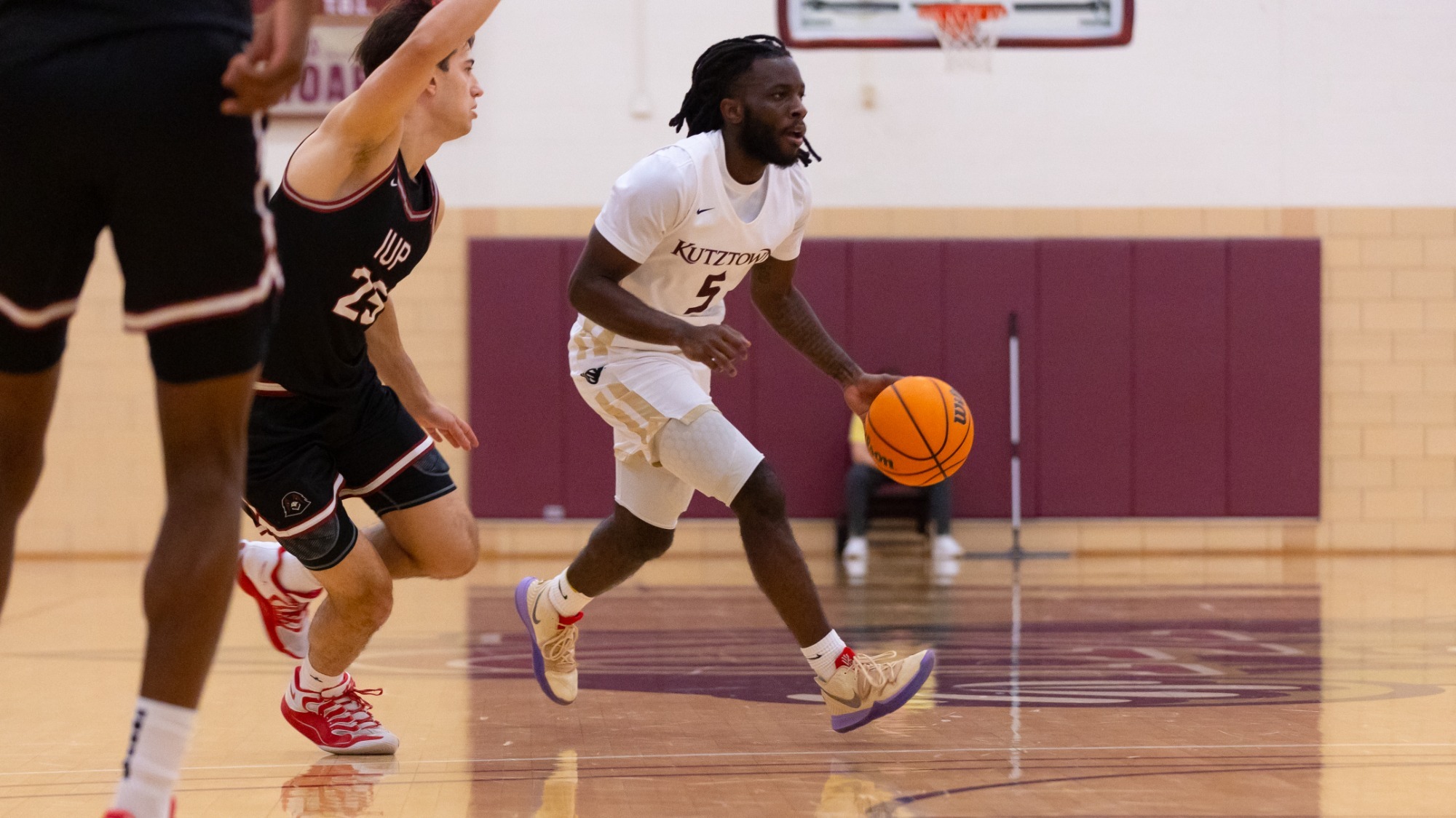 Jalen Bryant of the Kutztown University men's basketball team dribbles around an IUP defender during a PSAC crossover game at Keystone Arena on Friday, Dec. 5, 2025.