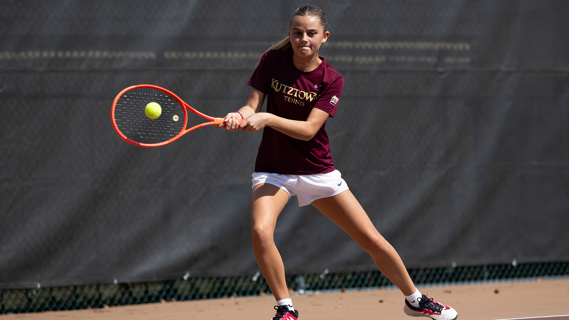 Maddie Gilbert of the Kutztown University women's tennis team hits a backhand shot during a match against Goldey-Beacom on Saturday, April 4, 2026.