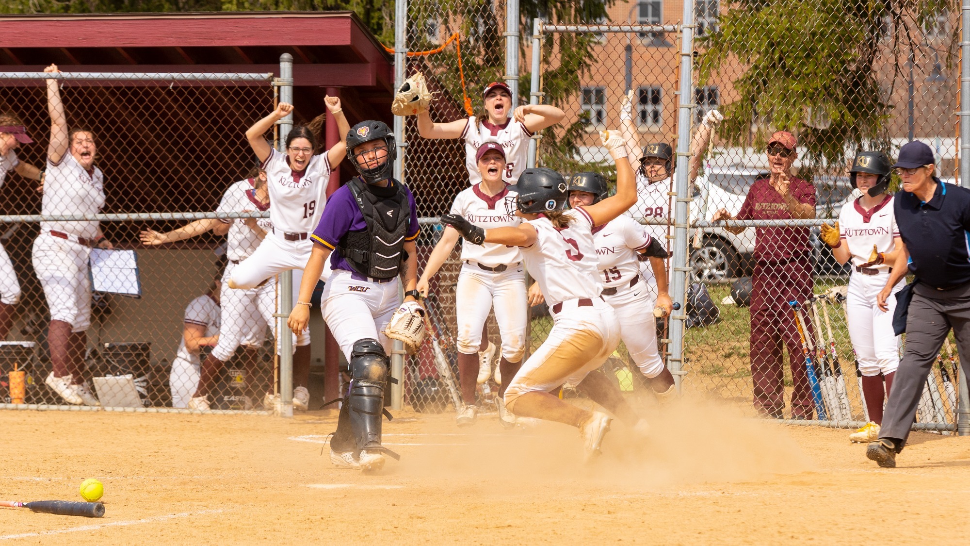 The Kutztown University softball team celebrates as Emily Henn scores the winning run in the bottom of the 10th inning to defeat West Chester, 4-3, on March 31, 2026.