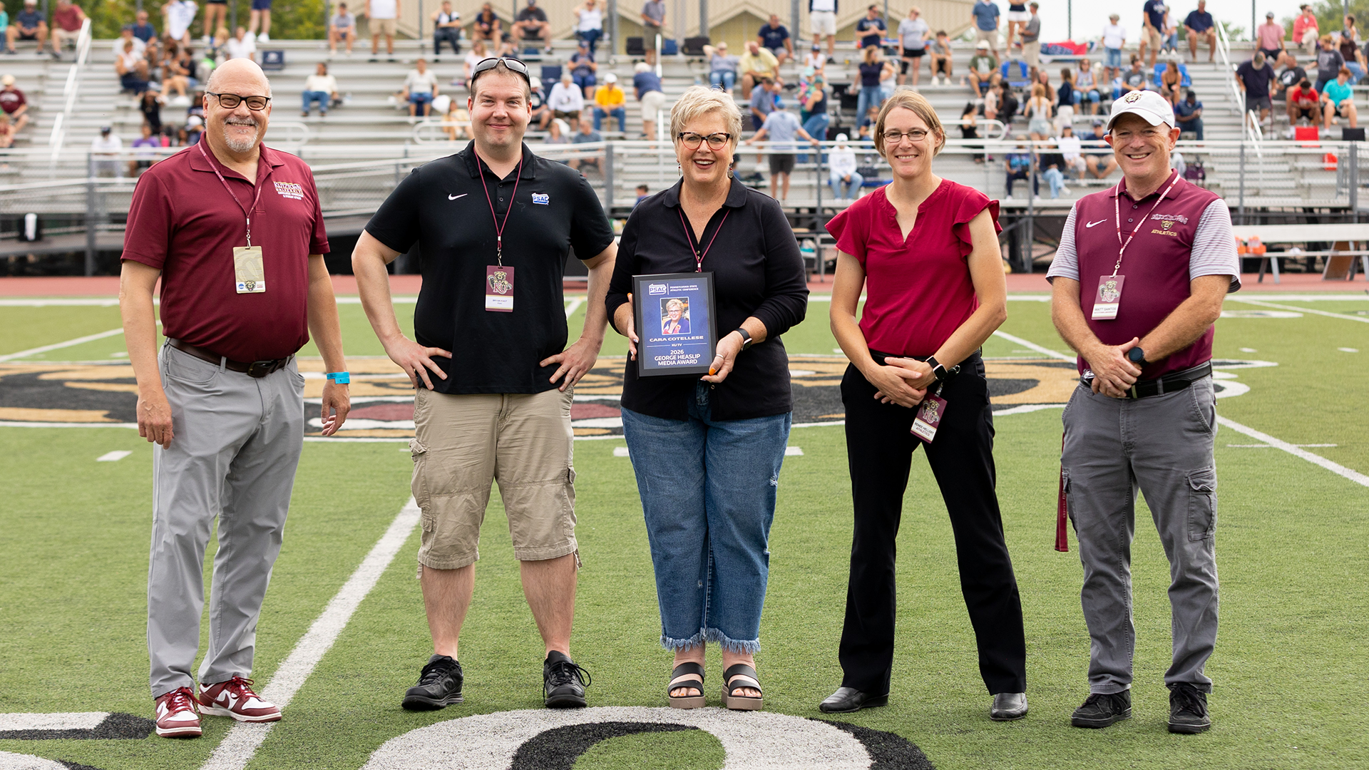 Former Kutztown University Department of Cinema, Television and Media Production Cara Cotellese (middle) was presented with the 2026 PSAC George Heaslip Media Award at halftime of Kutztown's football game against Clarion on Saturday, Sept. 12. Joining Cotellese for the presentation from left to right are KU president Dr. Philip Cavalier, PSAC assistant commissioner Bryan Kast, KU athletic director Renee Hellert and KU vice president for University Relations and Athletics Matt Santos.