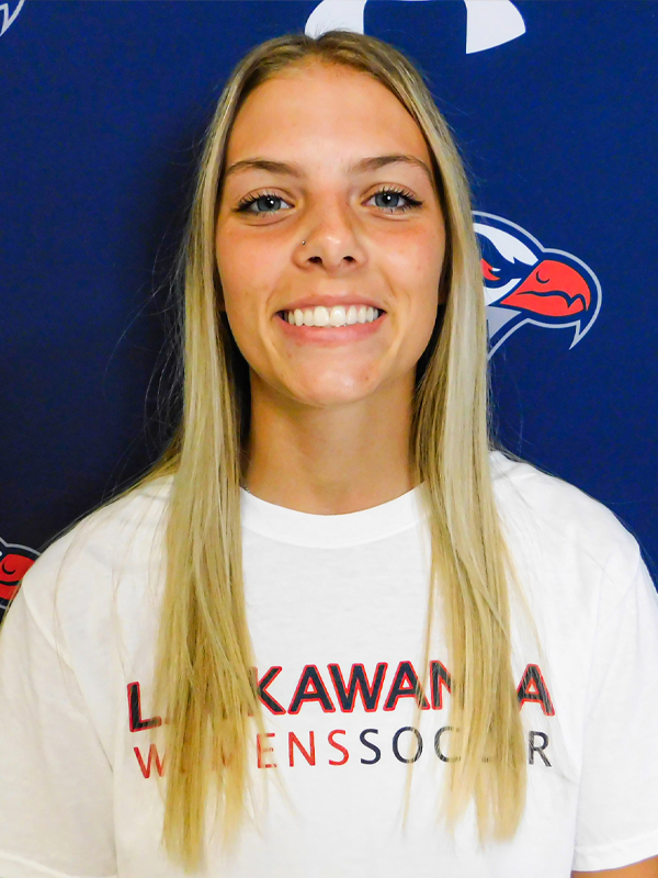 Assistant Women's Soccer Coach Ashley Bruno Standing In Front Of A Blue Lackawanna College Background.