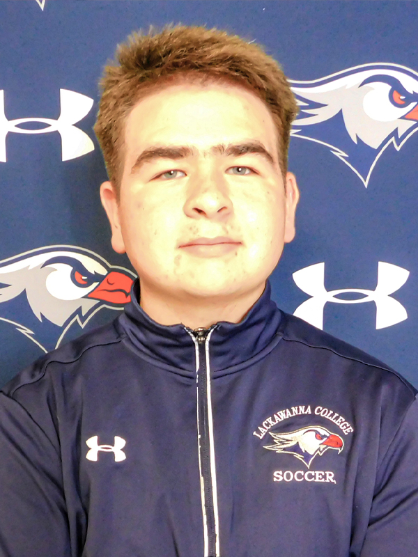 Lackawanna College Men's Soccer Team Manager Angelo Coniglio Standing In Front Of A Blue Lackawanna College Background.
