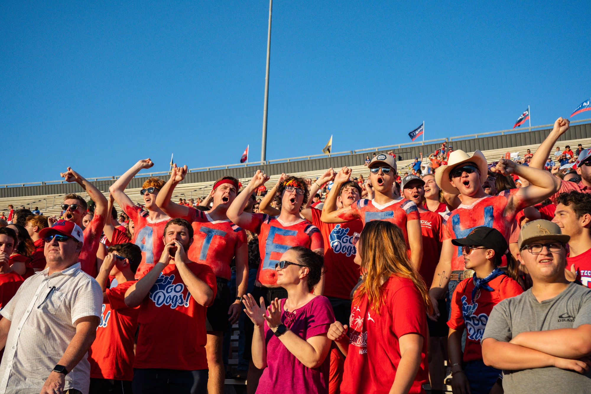 LA Tech students with red and blue body paint cheering in the stands