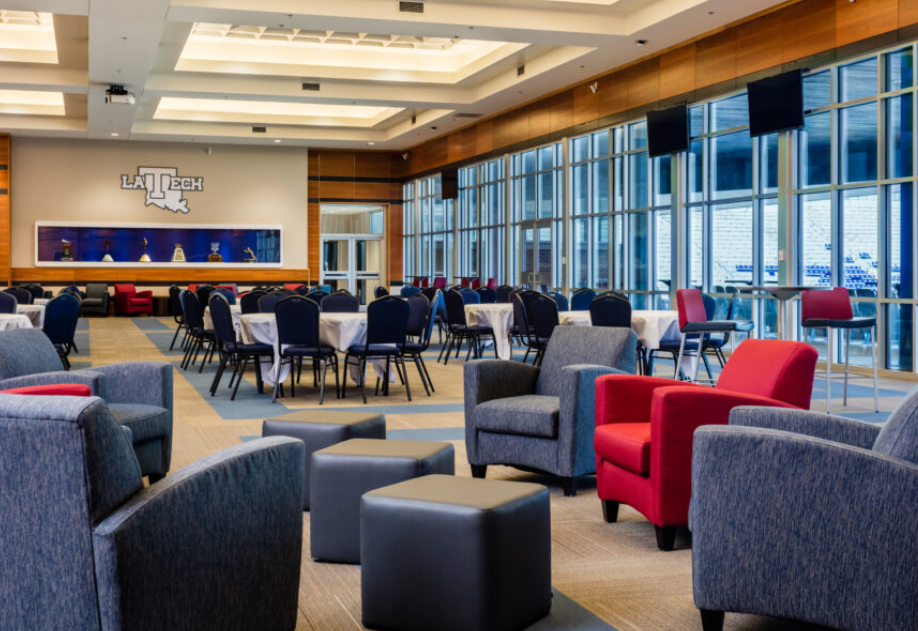 Indoor DAC Club area with round dining tables, lounge seating and windows overlooking the stadium