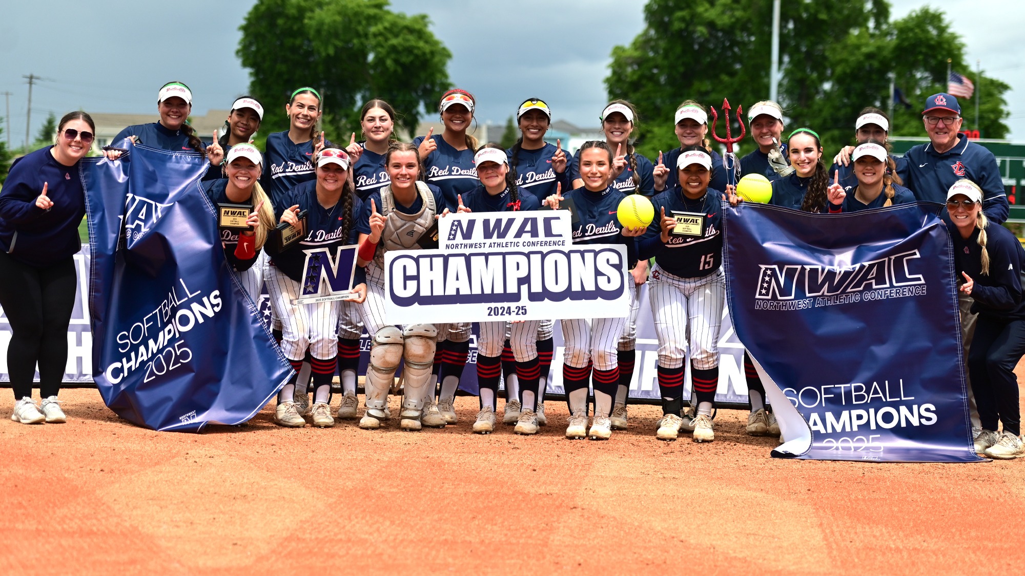 2025 Devils Softball Team pose with the NWAC Championship banner and trophy
