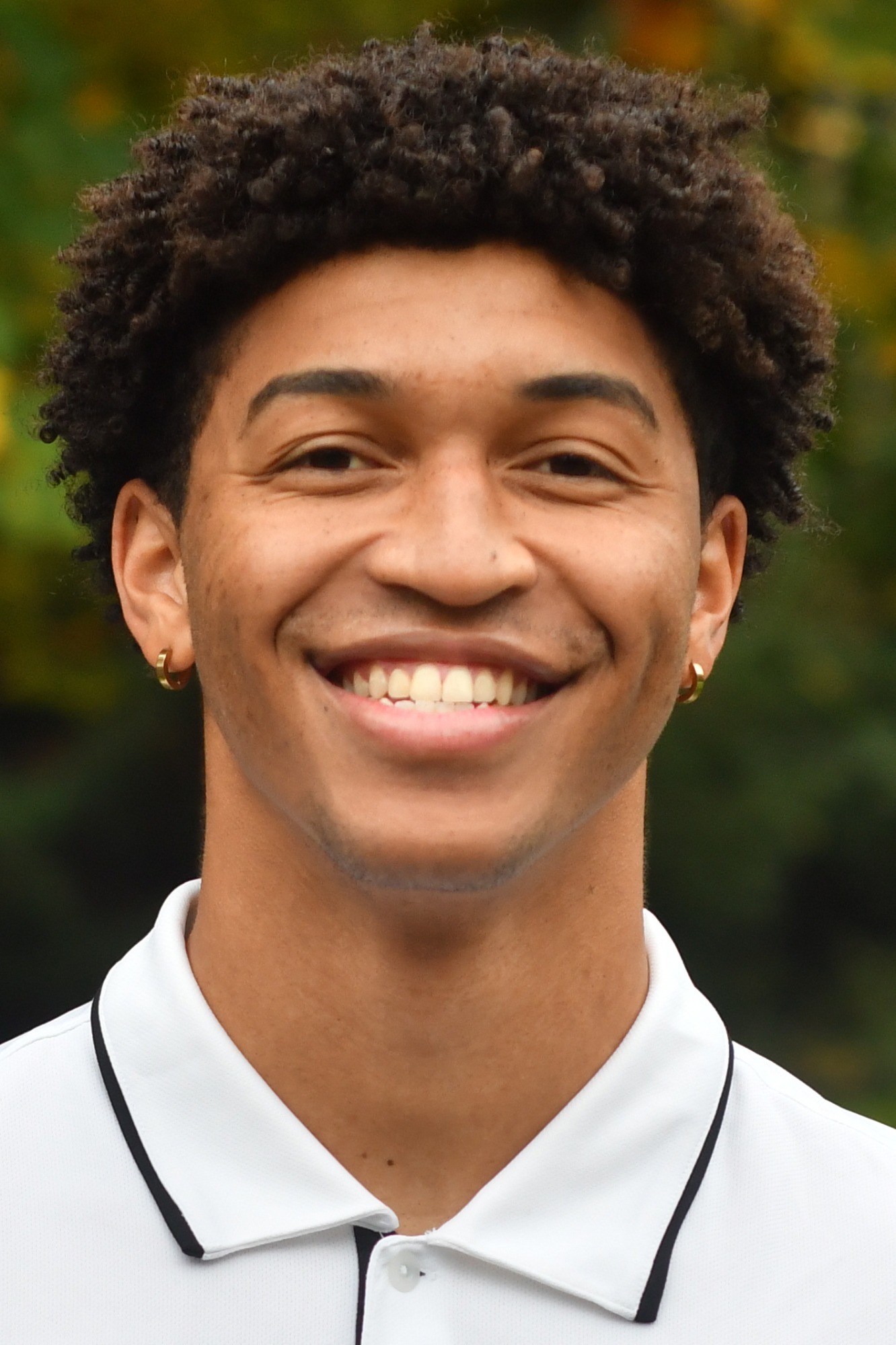 Jayden Simpson stands in front of a green background smiling. 