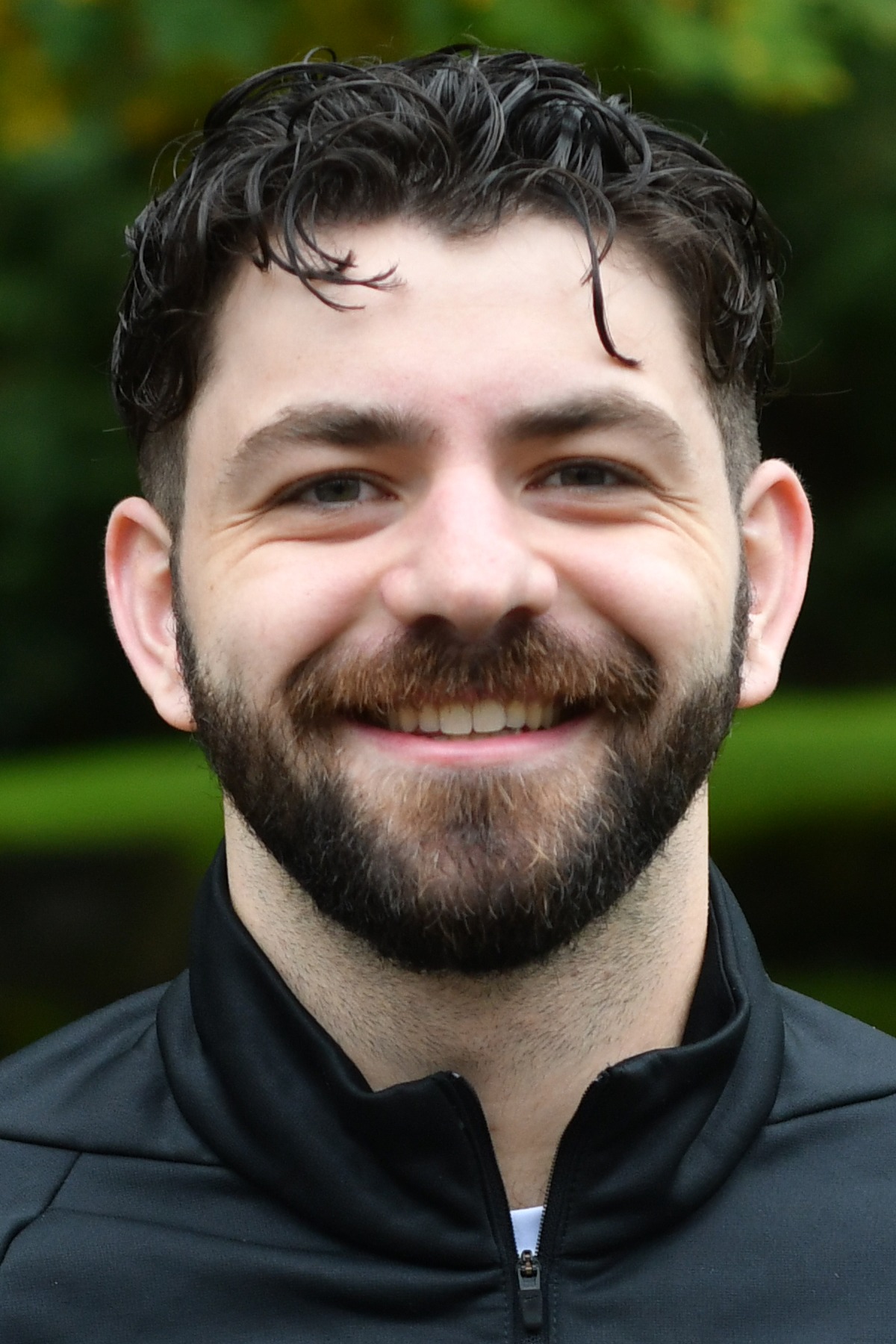 Michael Wudel stands in front of a green background smiling.