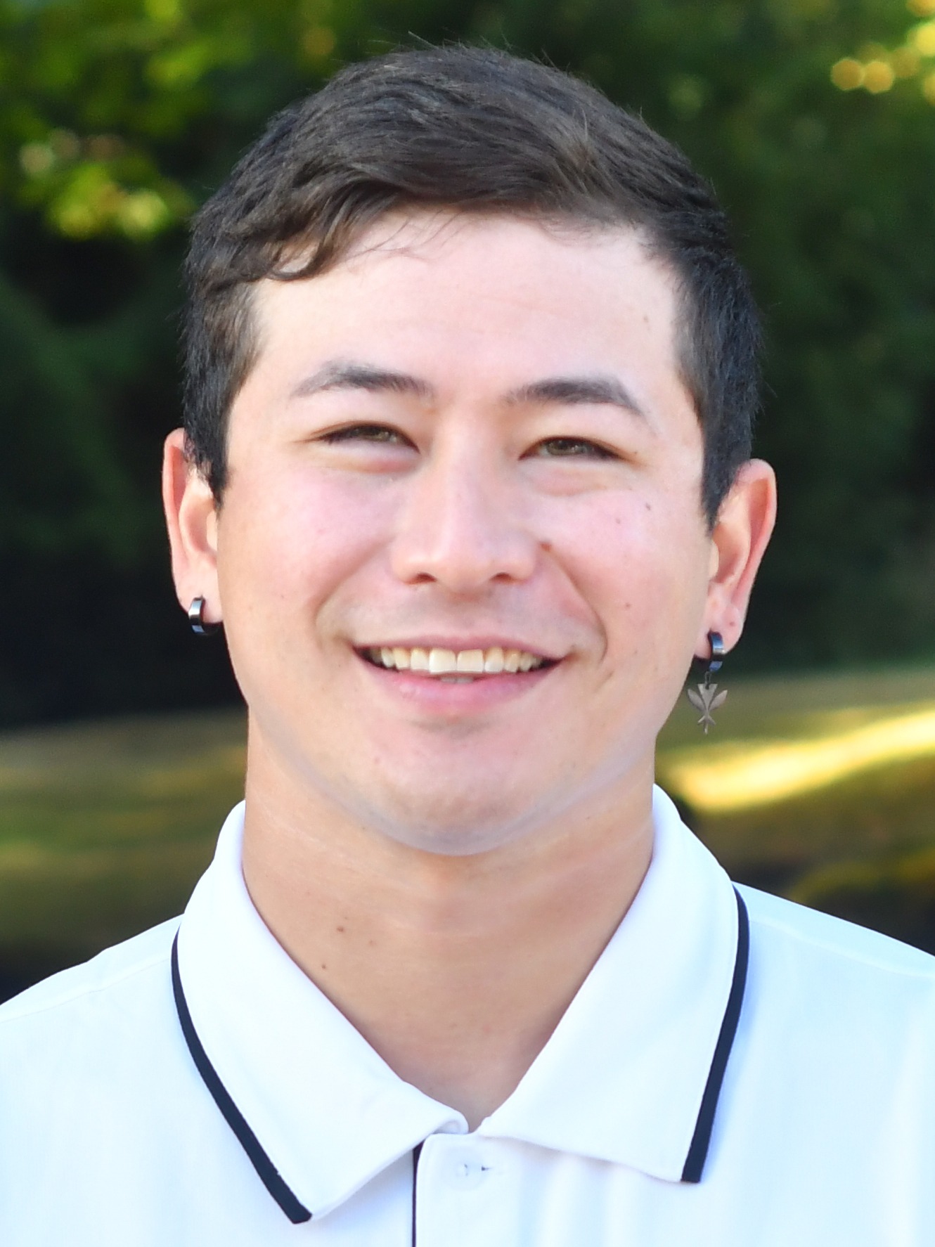 Evan Powers stands outside in front of a green background, smiling.