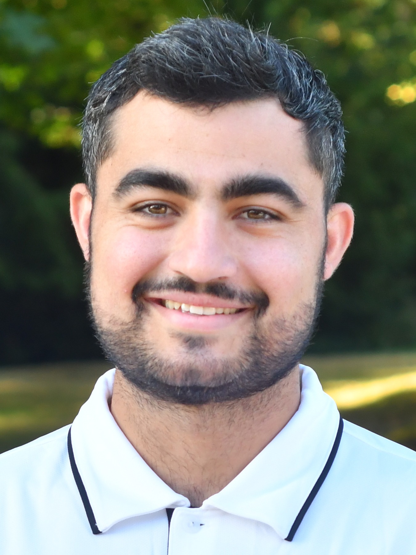Mike Machado stands outside in front of a green background, smiling.