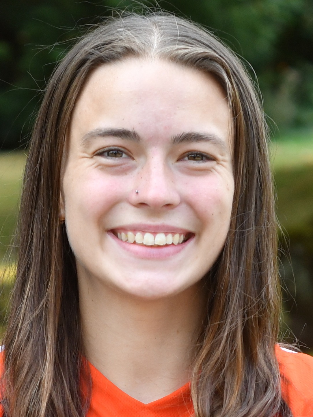 Macy O'Hara stands outside in front of a green background, smiling.