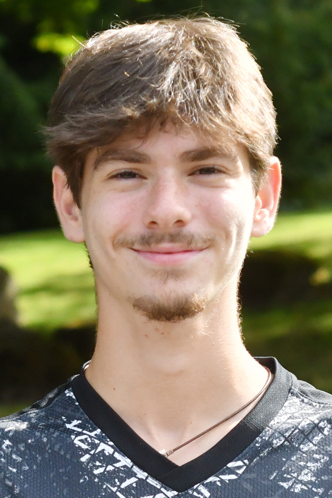 Noah Goodman stands outside in front of a green background, smiling.
