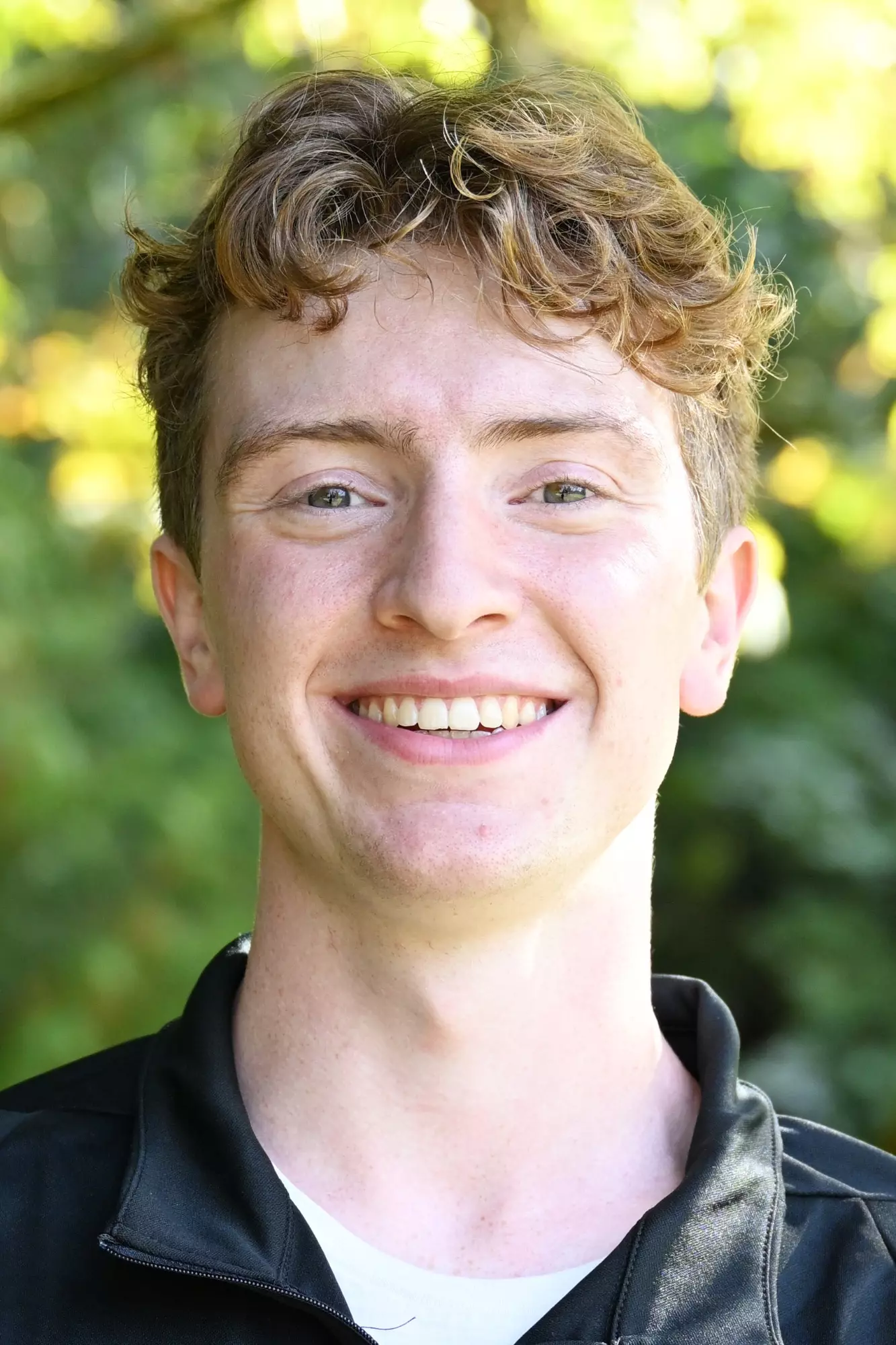 Micah Rysavy smiles in front of a green backdrop 