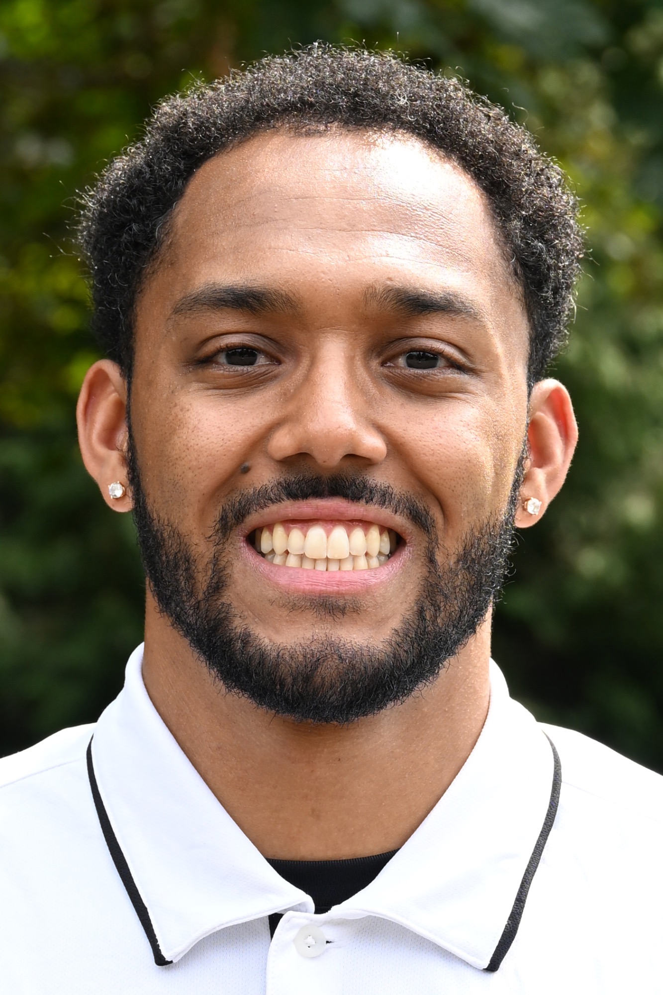 Tawayne Malone Jr. poses in front of a green background 