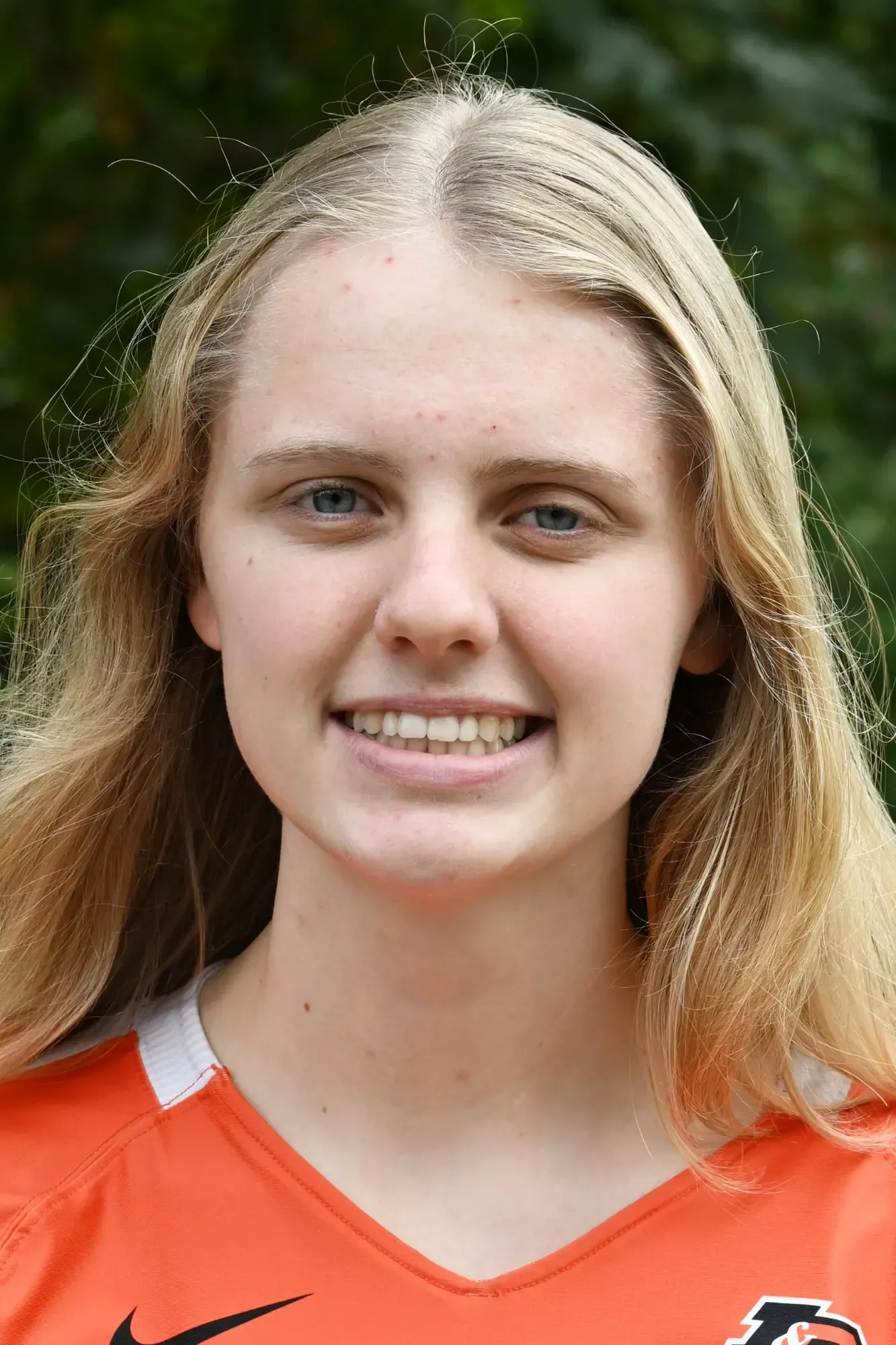 Emilie Thoreson stands in front of a green background, smiling.