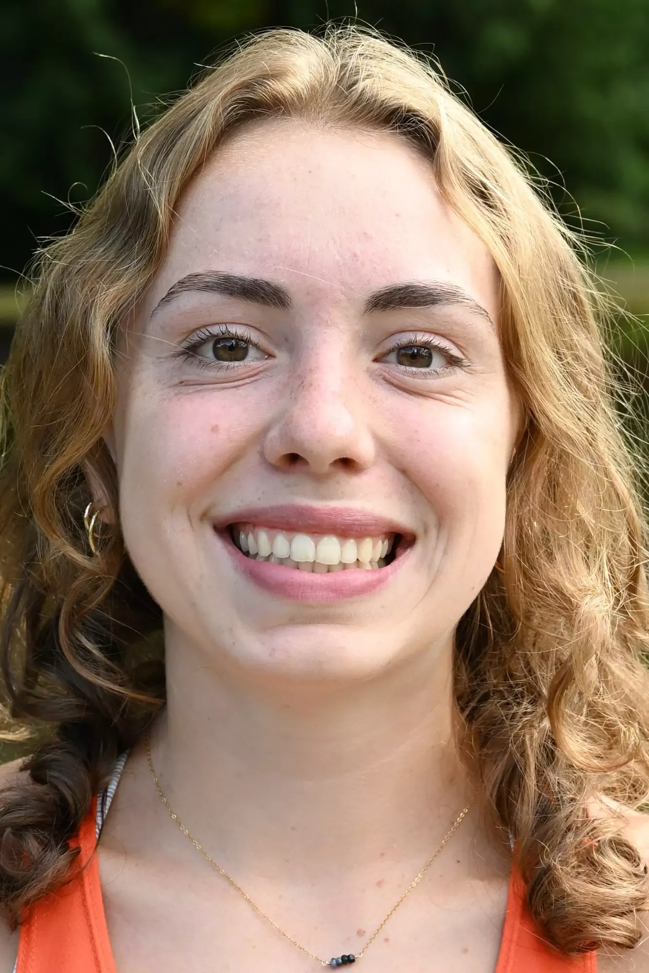 Riley Buese smiles in front of a green backdrop 