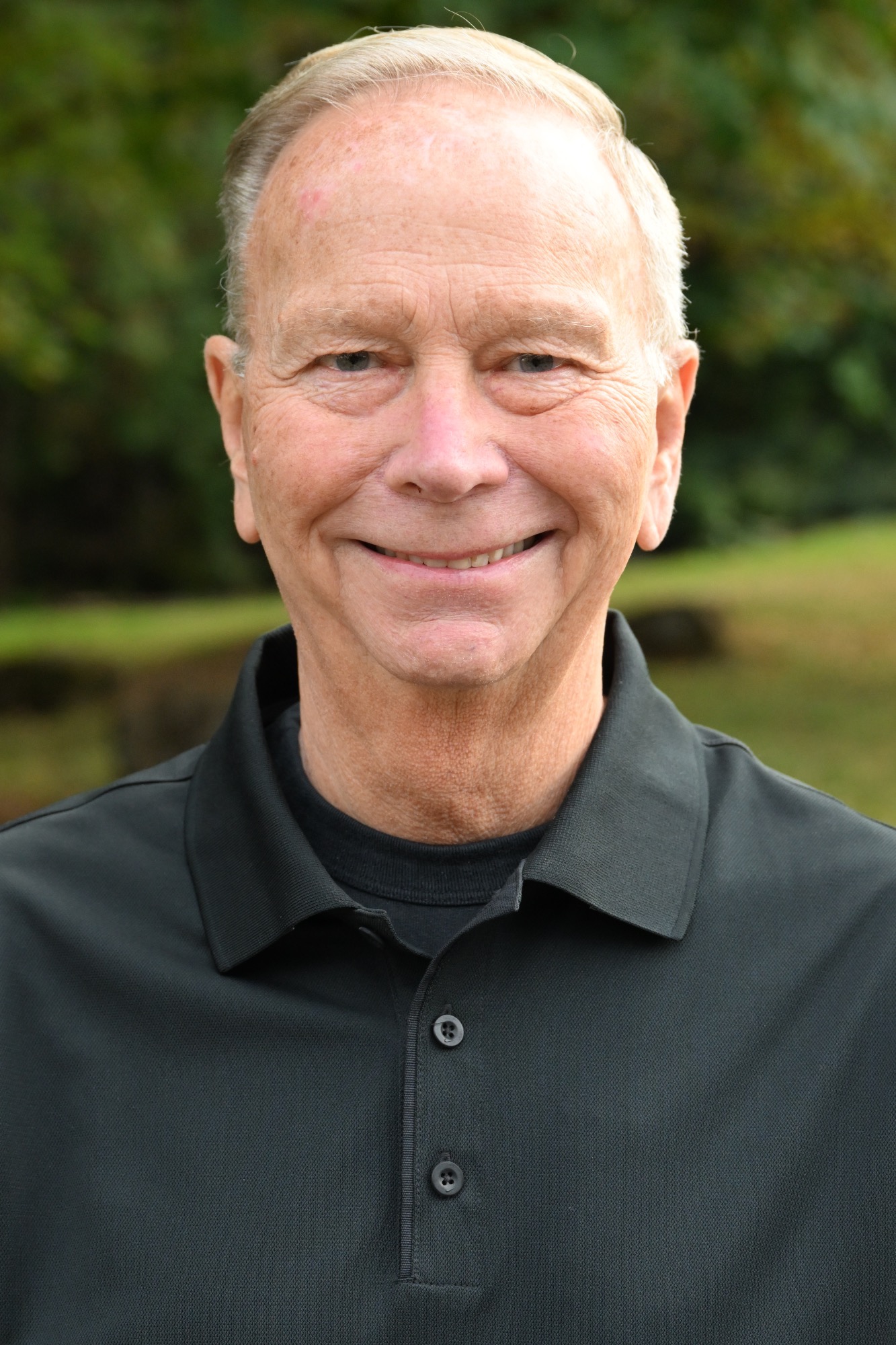 Mark Swenson smiles in front of a green backdrop 