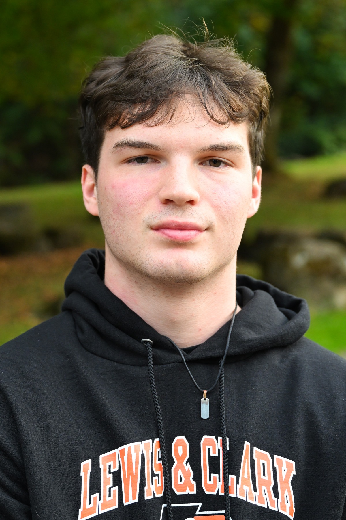 Atticus Kelly stands in front of a green background smiling