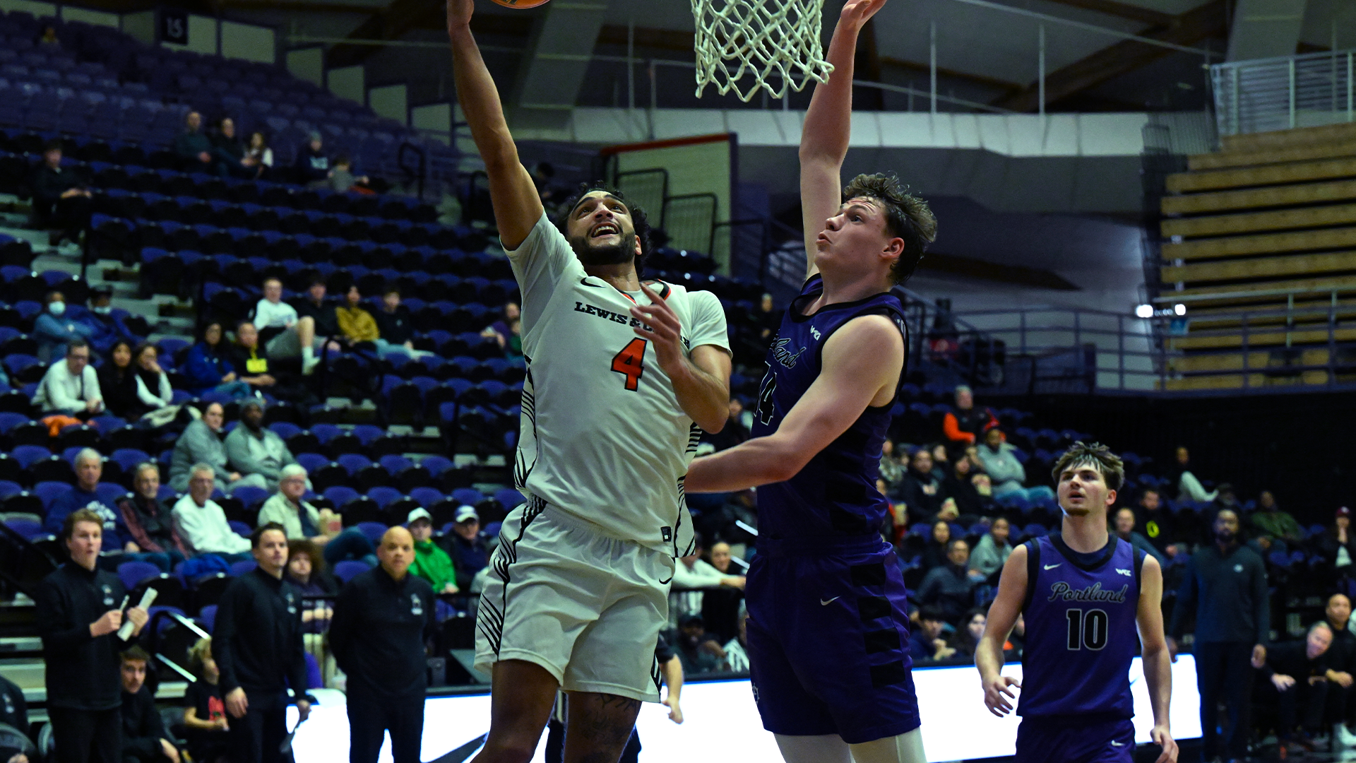 Andre Treadwell wearing white goes up to the basket against a defender in purple. 