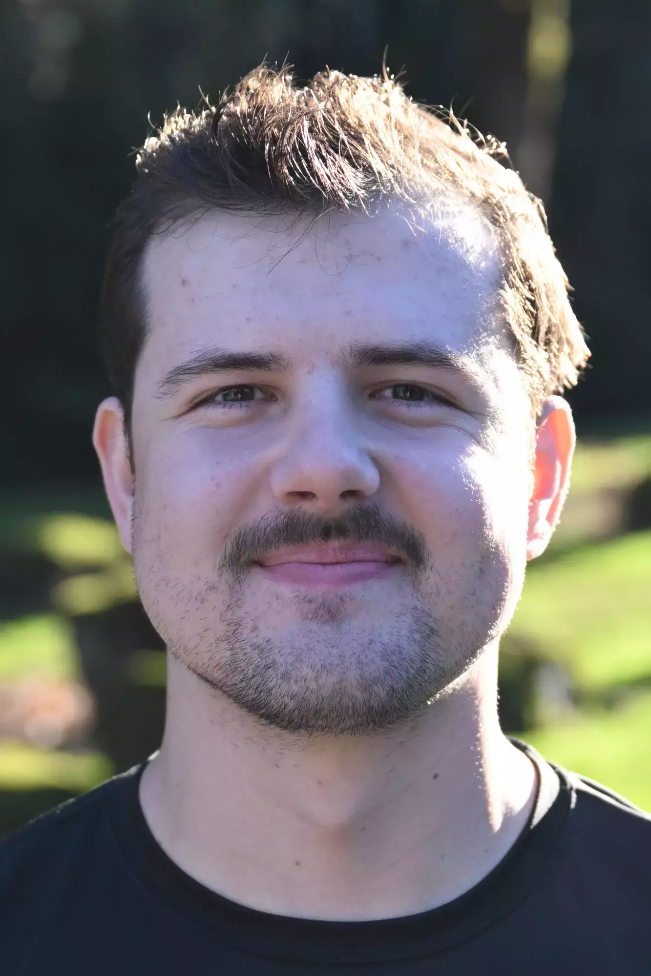 Will Heron smiles in front of a green backdrop 