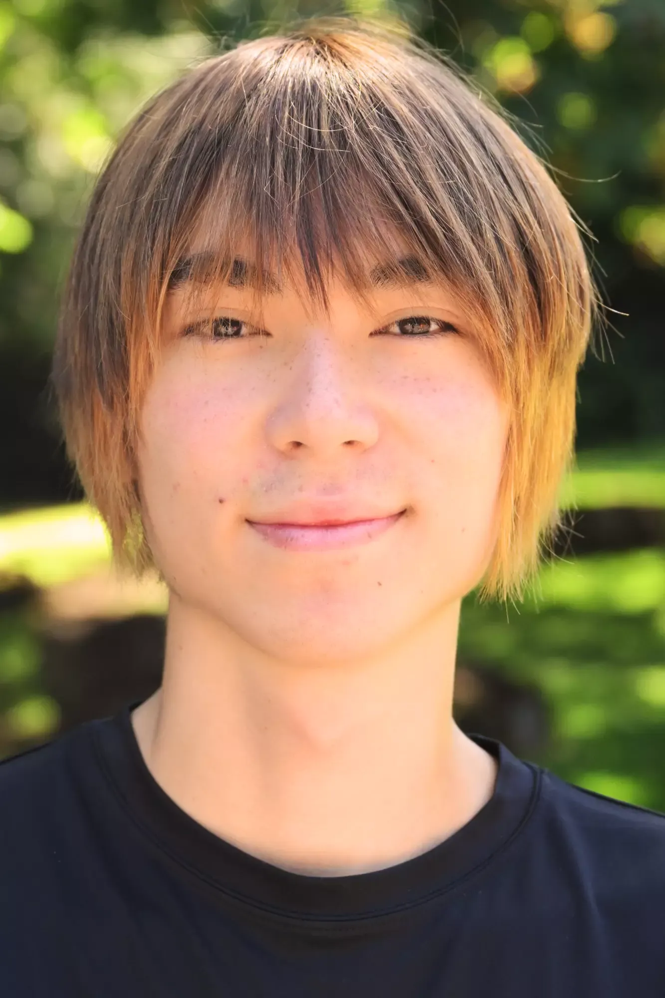 Theo Ye Headshot stands in front of green background smiling.