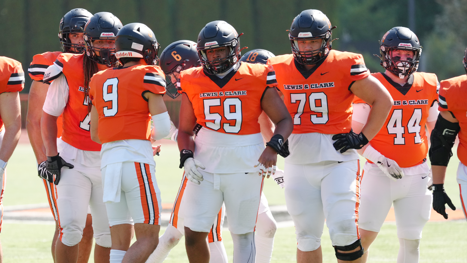 Football's offensive line stands up in the huddle before a play