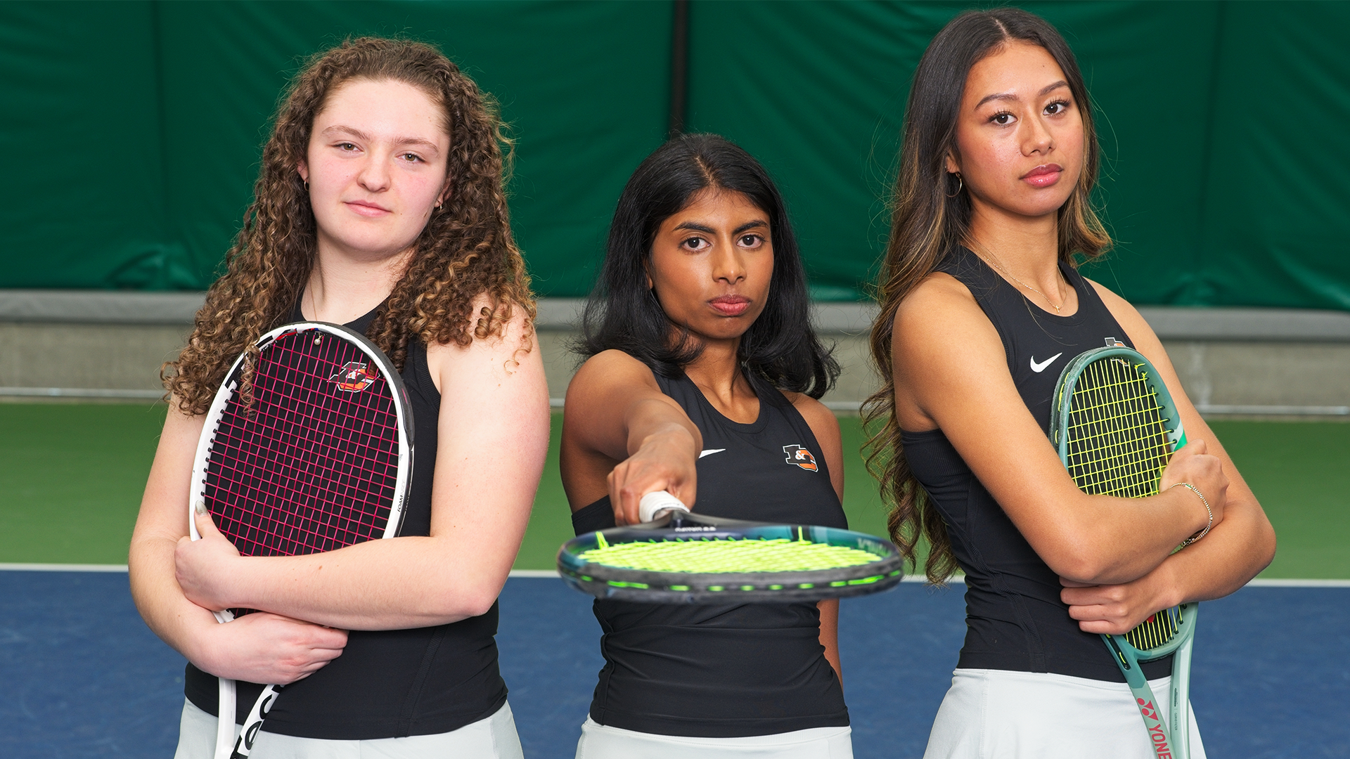 Emma Loucks, Susanna Anand and Charlotte Makoni stand together on the tennis court.