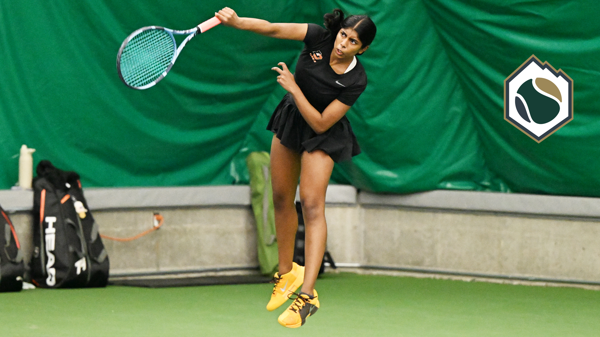 Susanna Anand jumps and hits a serve