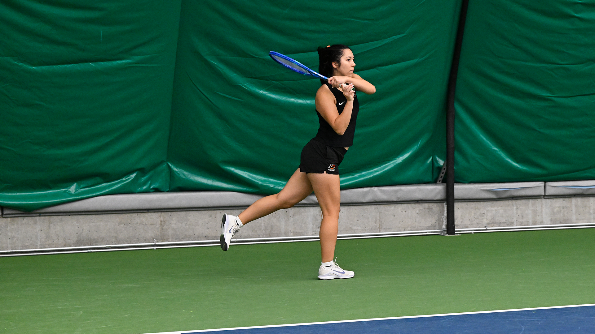 Alex Mignogna hits a baseline backhand shot against an opponent. 