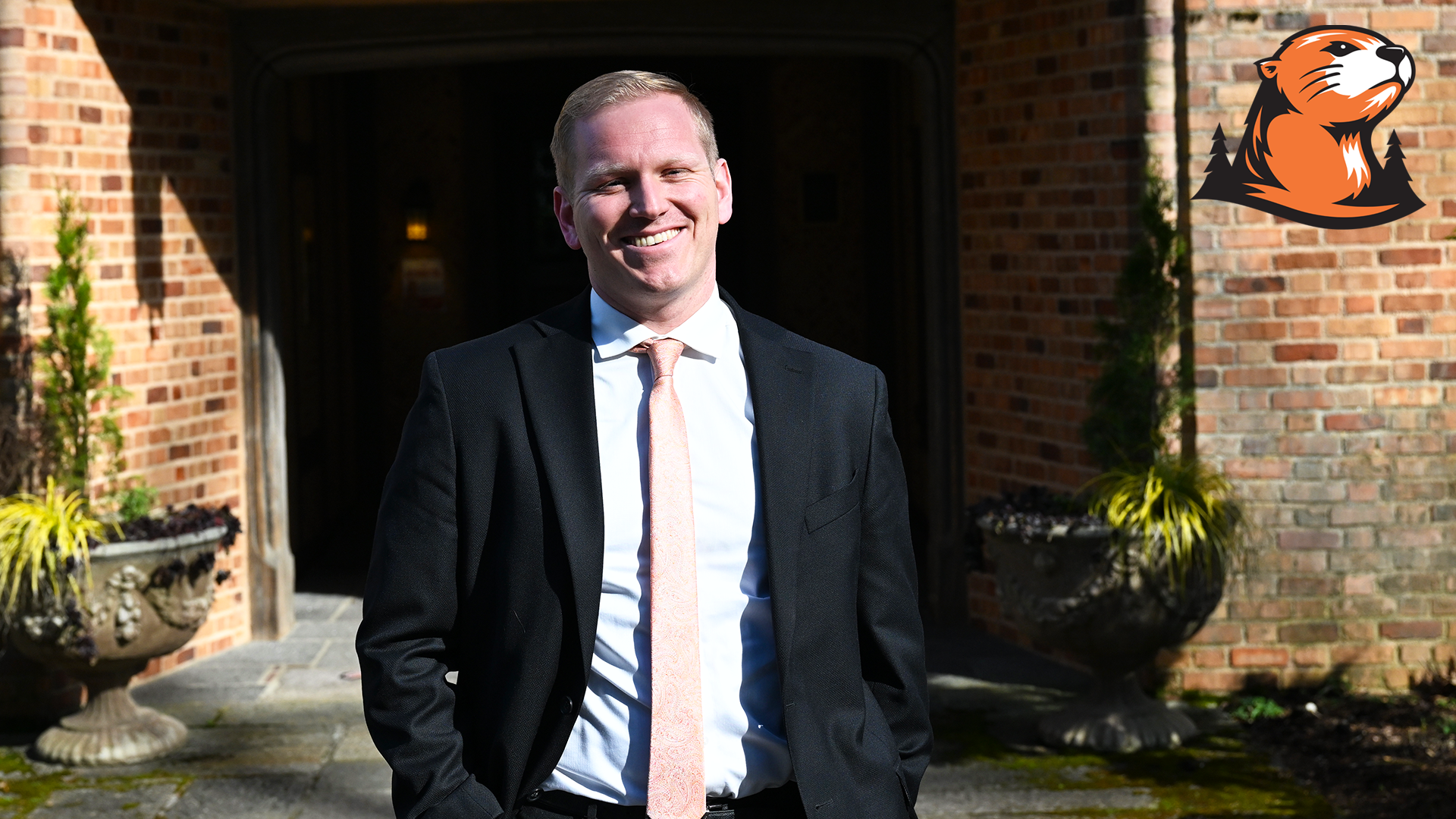 Cory Coombe smiles in front of the Manor House on the Lewis & Clark campus. 