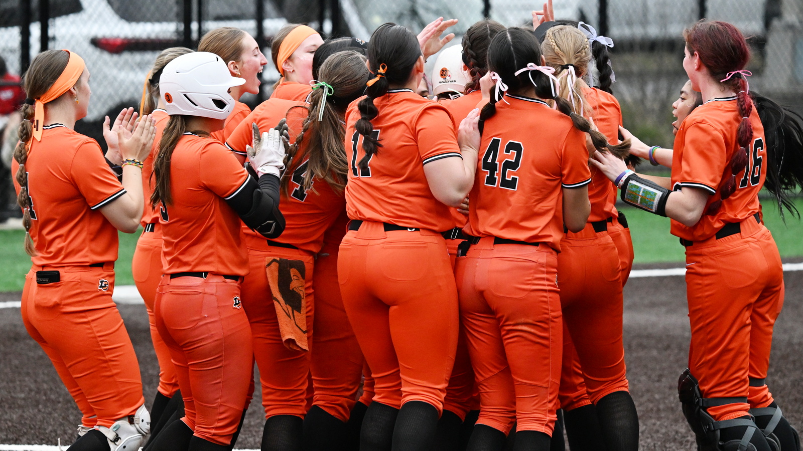 Softball players huddle up and celebrate after Madison Scroggins' walk-off single against the College of St. Benedict