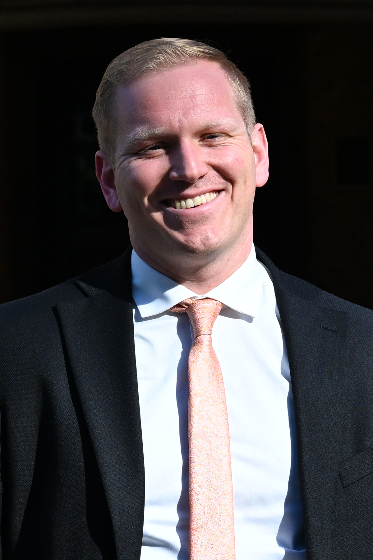 Cory Coombe stands in front of the manor house smiling. 