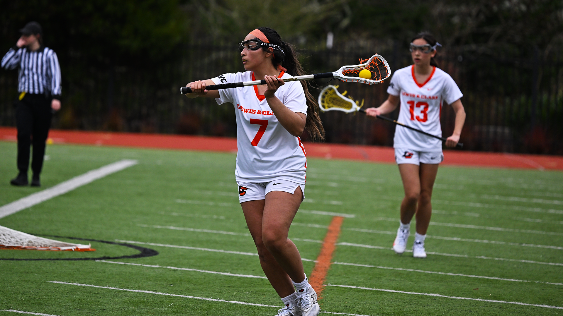 Aviana Gonzales, in the foreground cradles the ball in her stick, while Ala Cross in the back ground looks on. 
