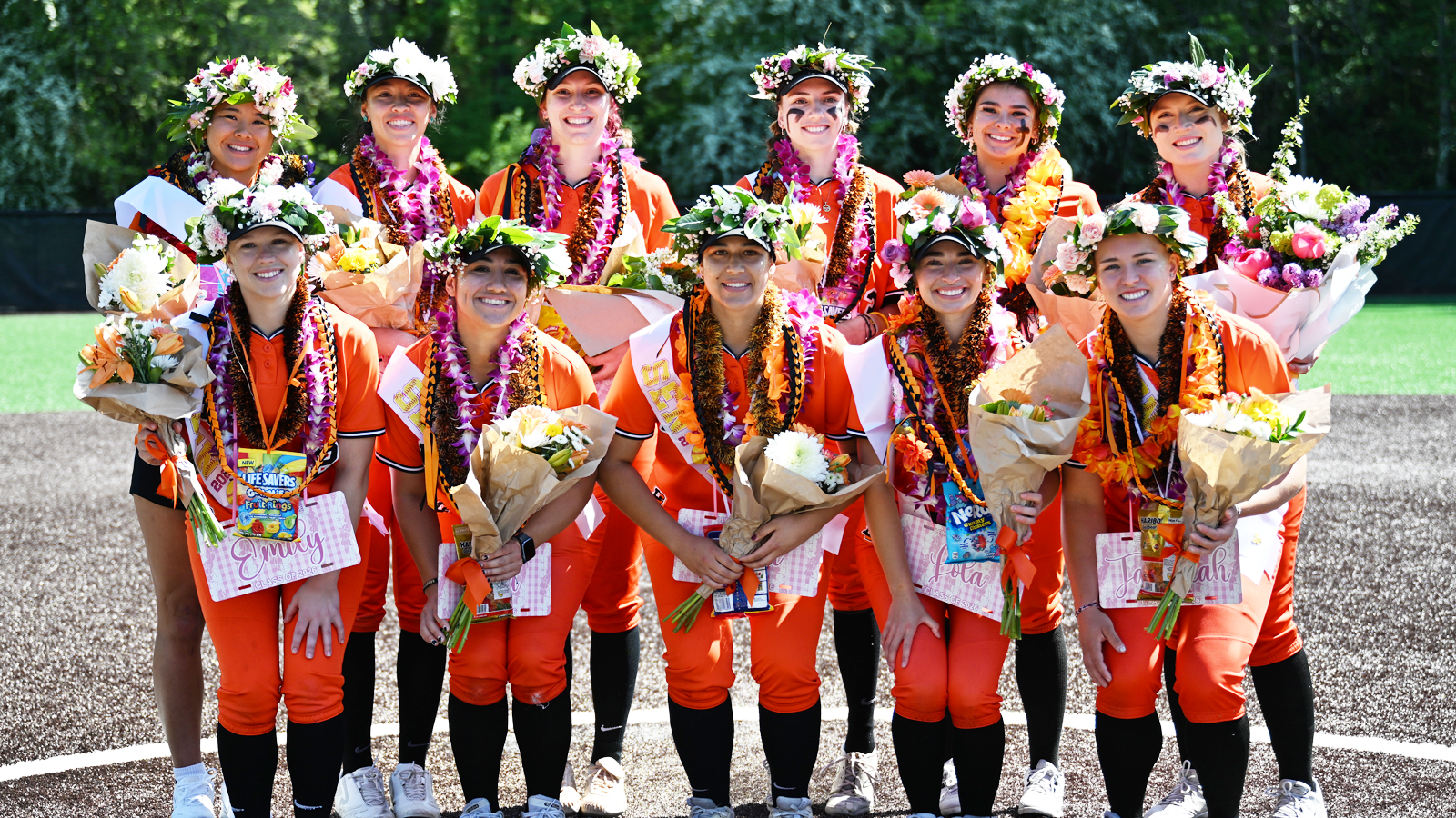 Softball's 11 seniors pose for a photo together on the field 