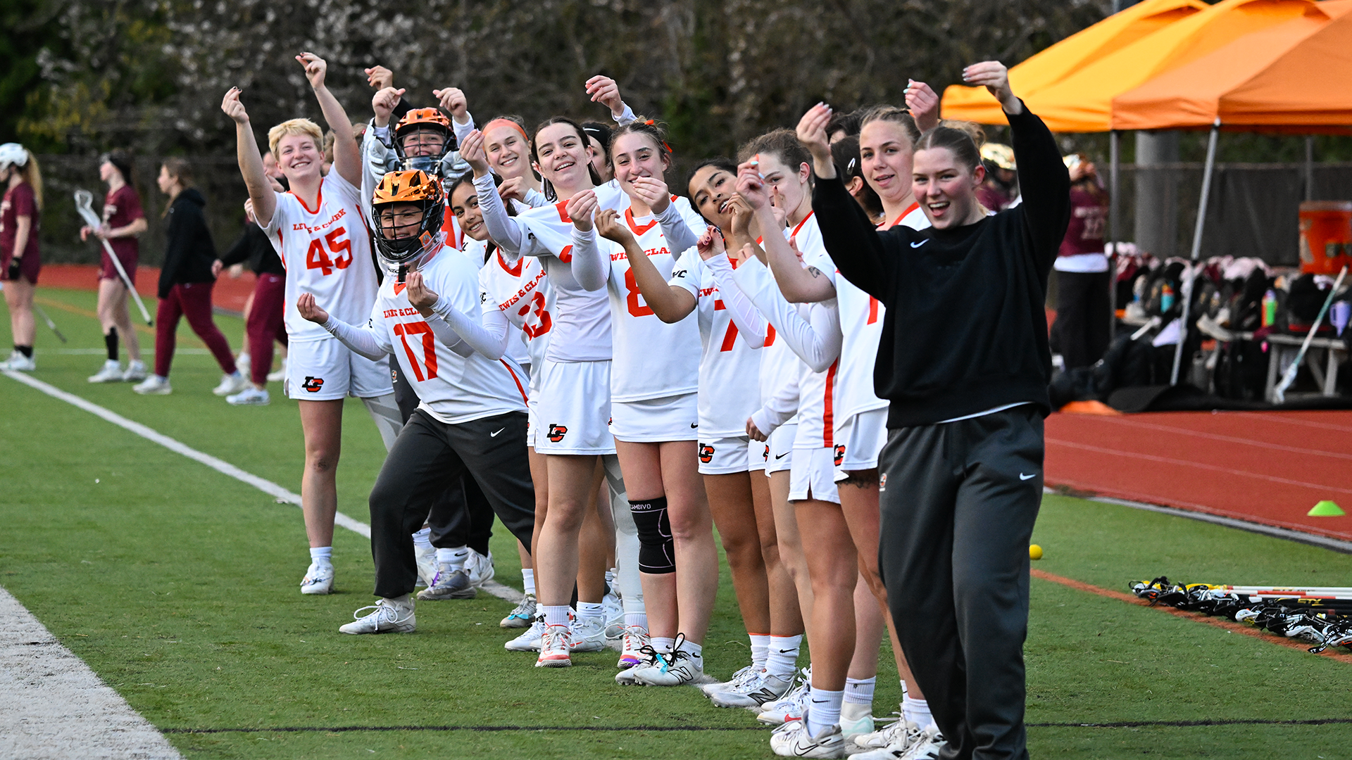 The women's lacrosse team celebrates on the sideline ahead of a game. 