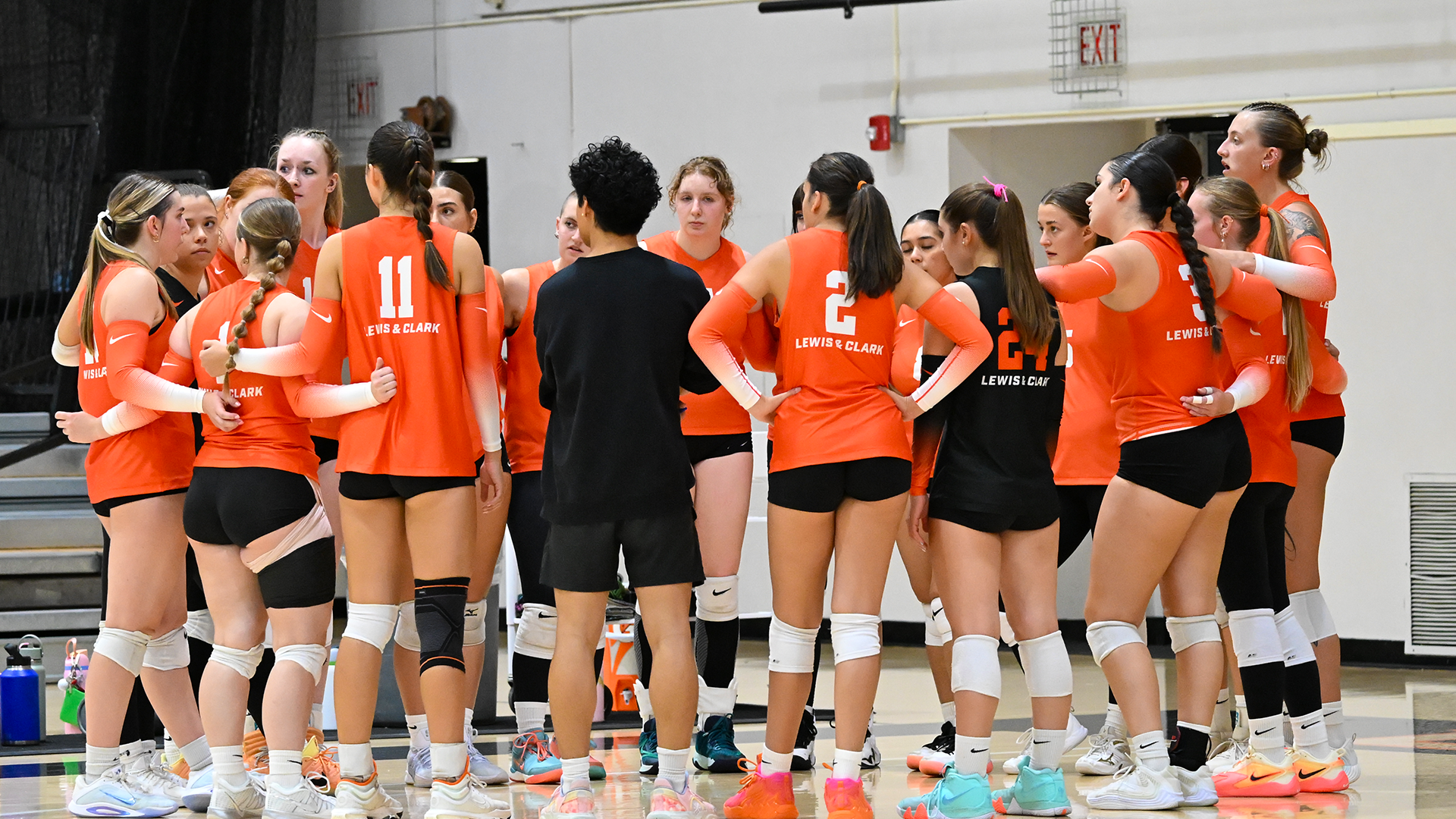 The volleyball team huddles up during a timeout. 