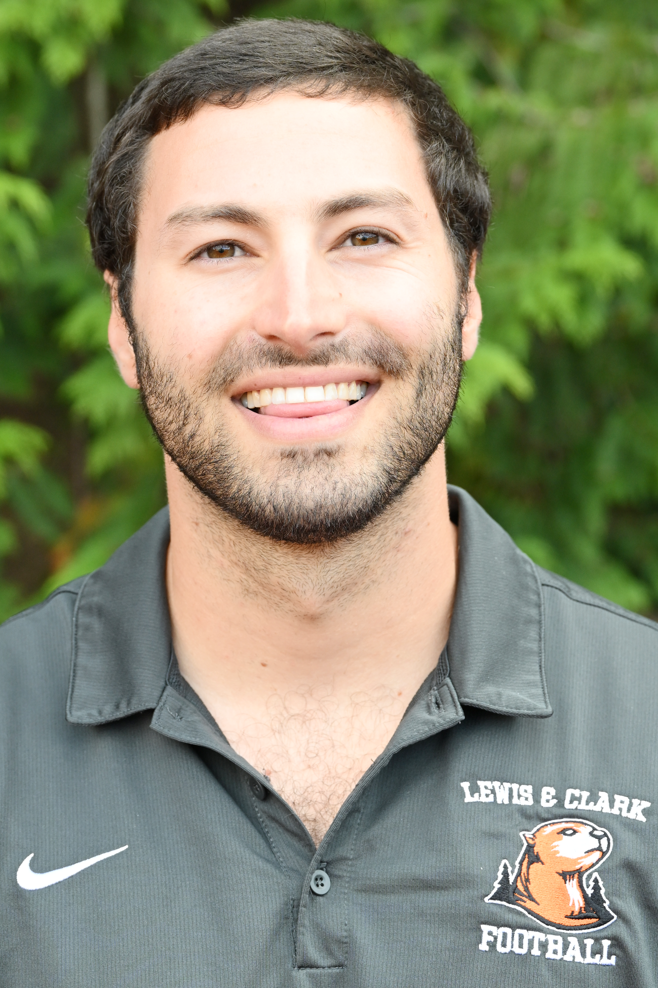 Andrew Segre smiles in front of a green backdrop 