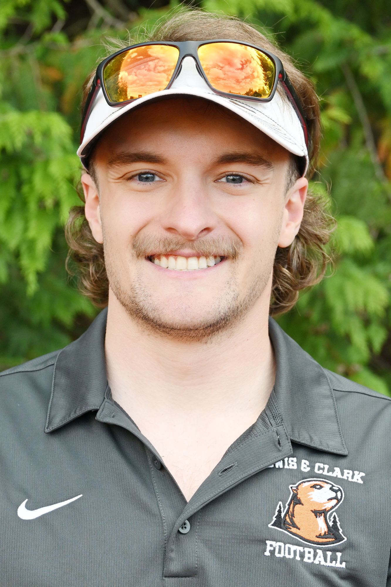 Chance Hansen smiles in front of a green backdrop 
