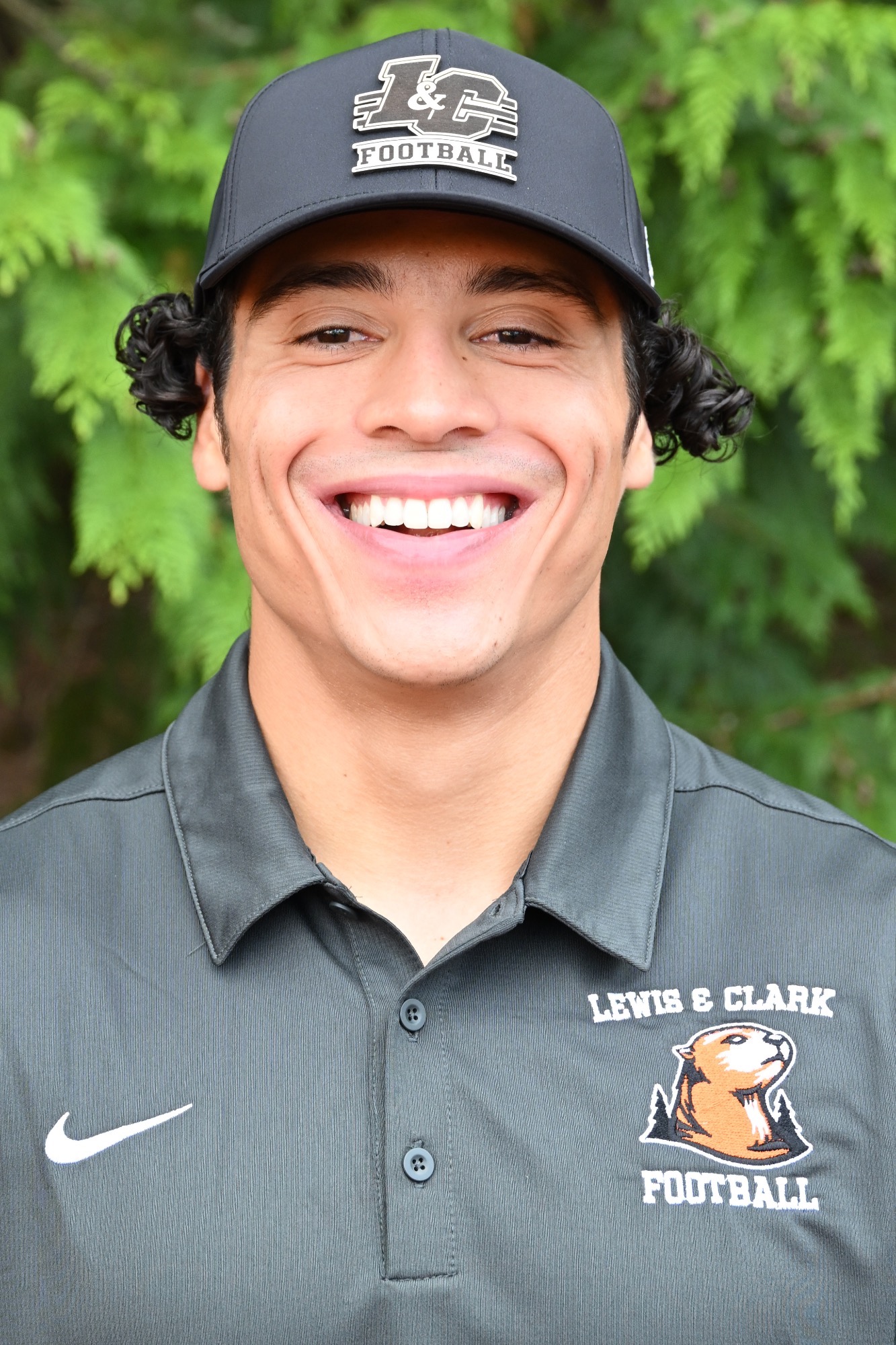 Tyler Epefanio smiles in front of a green backdrop 