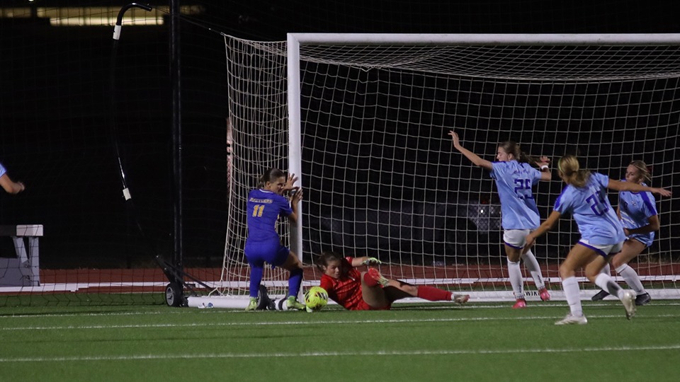This is a photo of Lubbock Christian goalkeeper Emma Wright (red uniform, #1) making a save against a St. Mary's attacker while LCU defenders look on. 