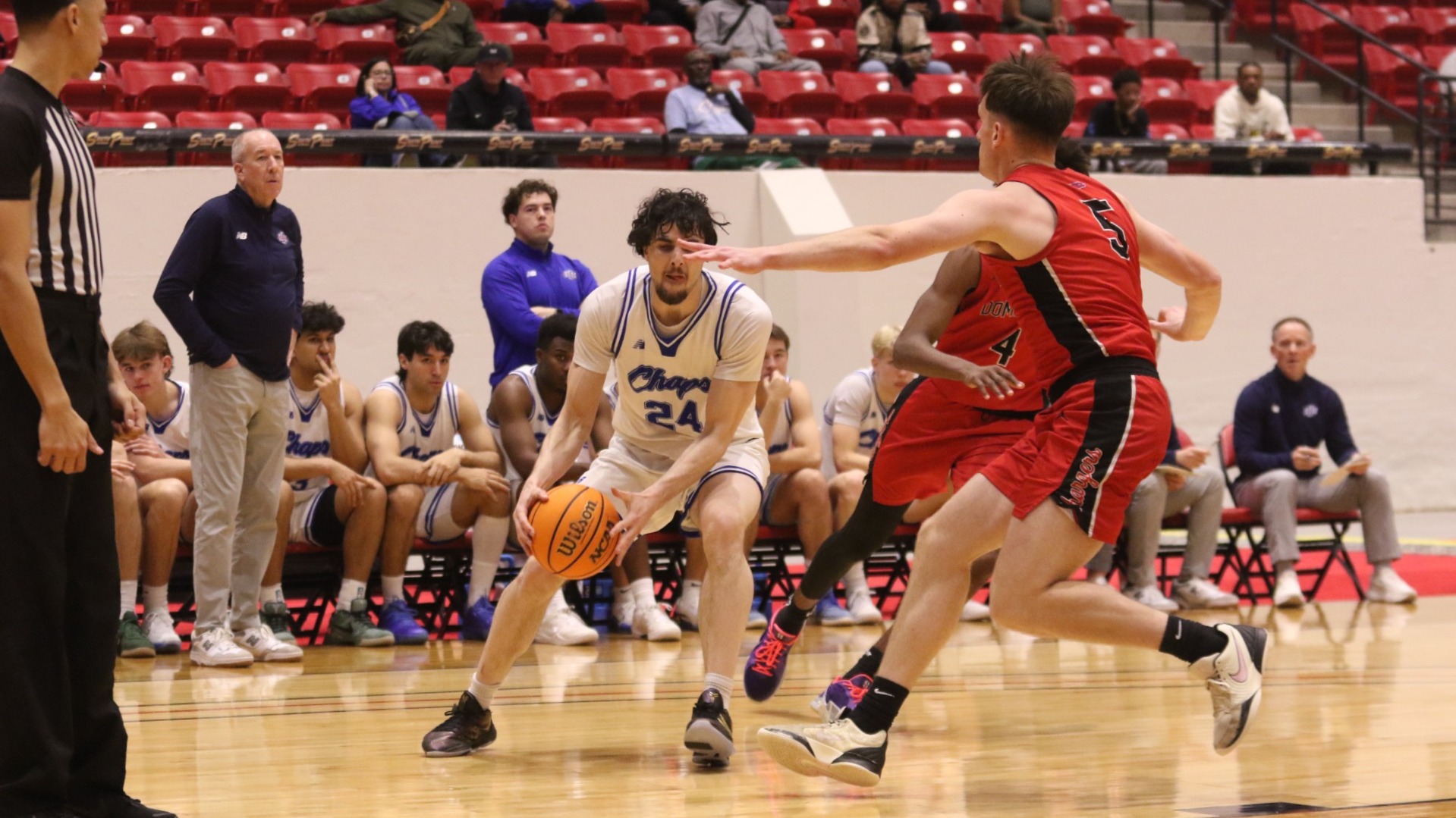 This is a photograph of Lubbock Christian men's basketball player Antonio Pusateri (white jersey, #24) grabbing the basketball while being defended by a Dominican (red jersey) player at the South Point Arena. 