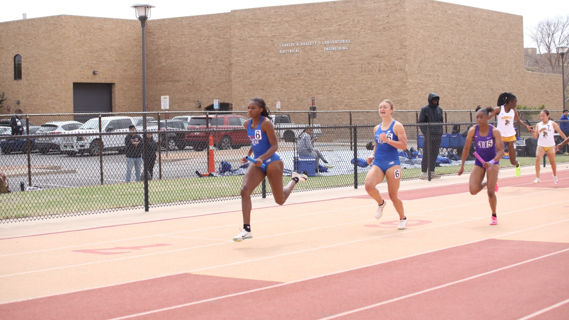 Photo of Lubbock Christian University track athletes, Anna Salisbury and Anika Beukes, during the Masked Rider Open at Texas Tech. Beukes is seen handing off the baton to Salisbury during a relay event.